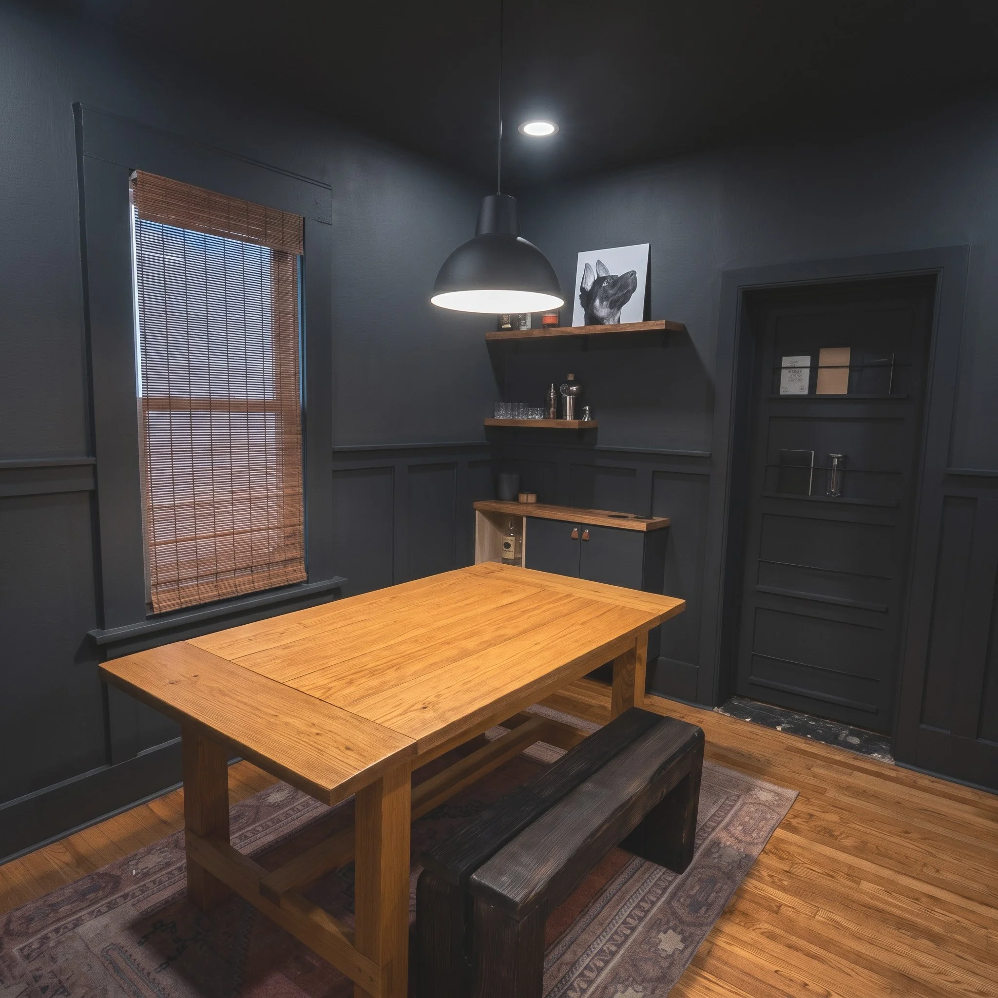 Interior view of a modern dining room with a rectangular wooden table, black cushioned benches, dark gray walls, a window with bamboo blinds, a wall shelf with decorative items, a painting of a dog, and ceiling lights.