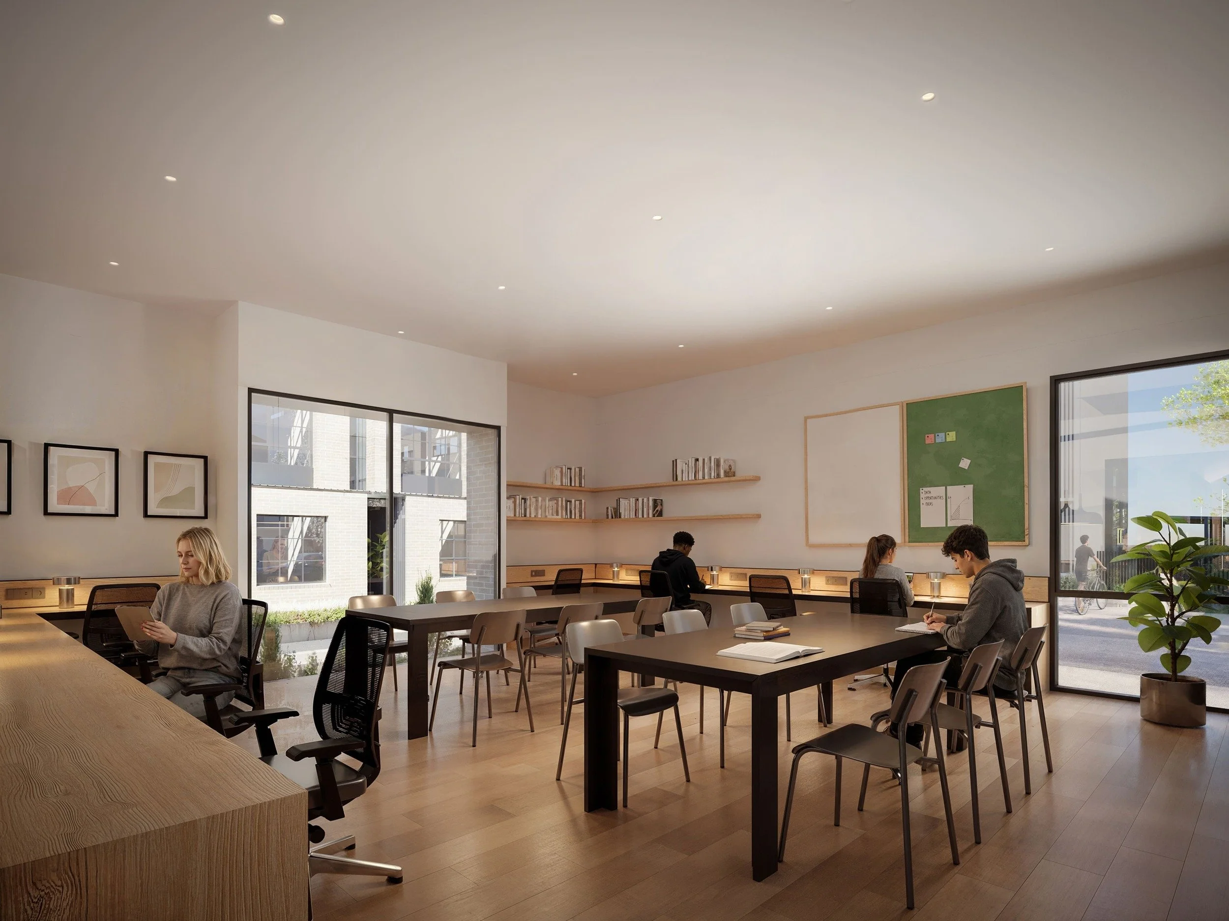 A modern coworking space with large windows, wooden flooring, and minimalist decor. Several people are working or reading at tables, with wall art and bookshelves visible.