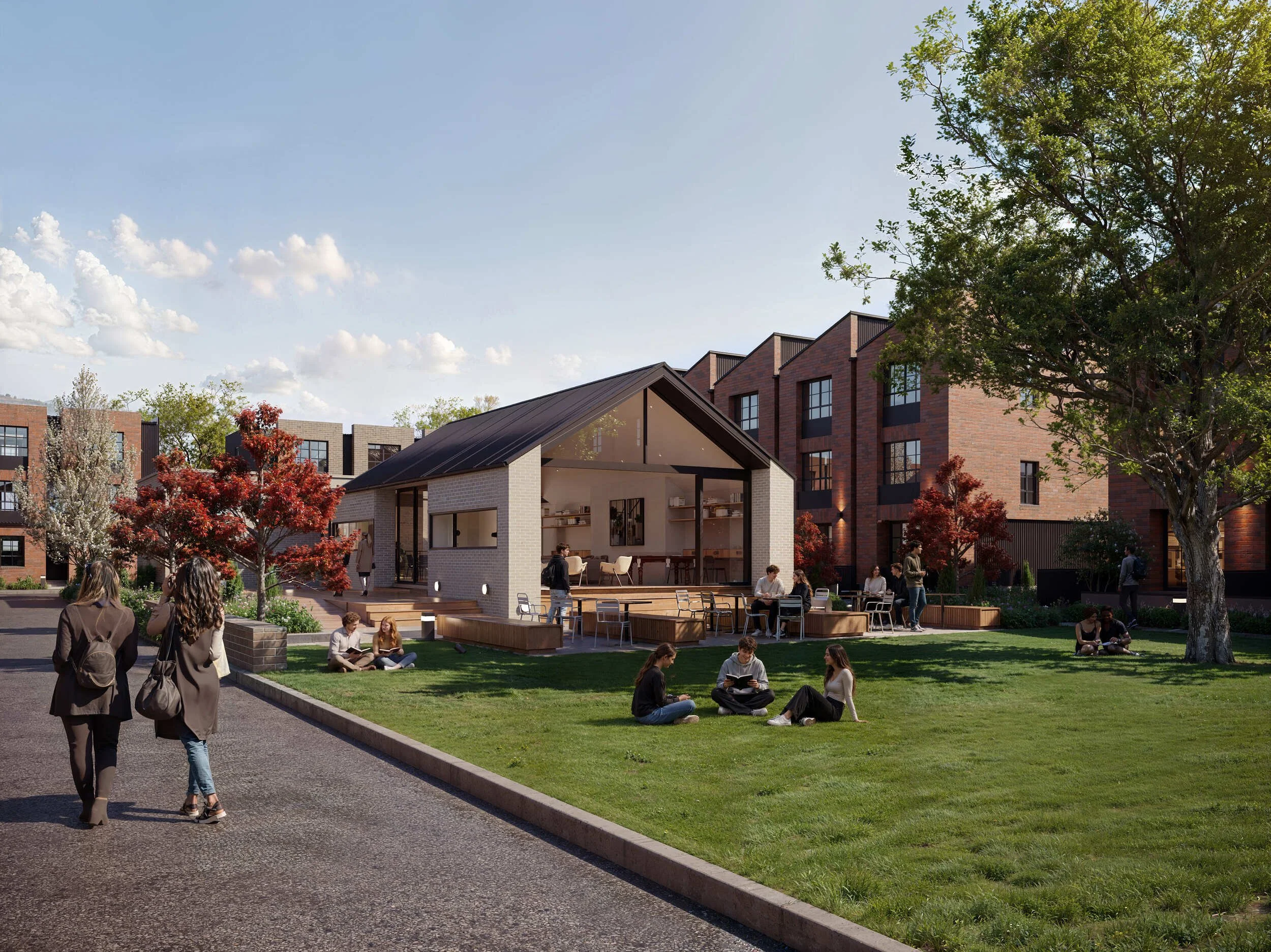 People sitting on a grassy lawn and walking in front of modern brick apartment buildings under a partly cloudy sky.