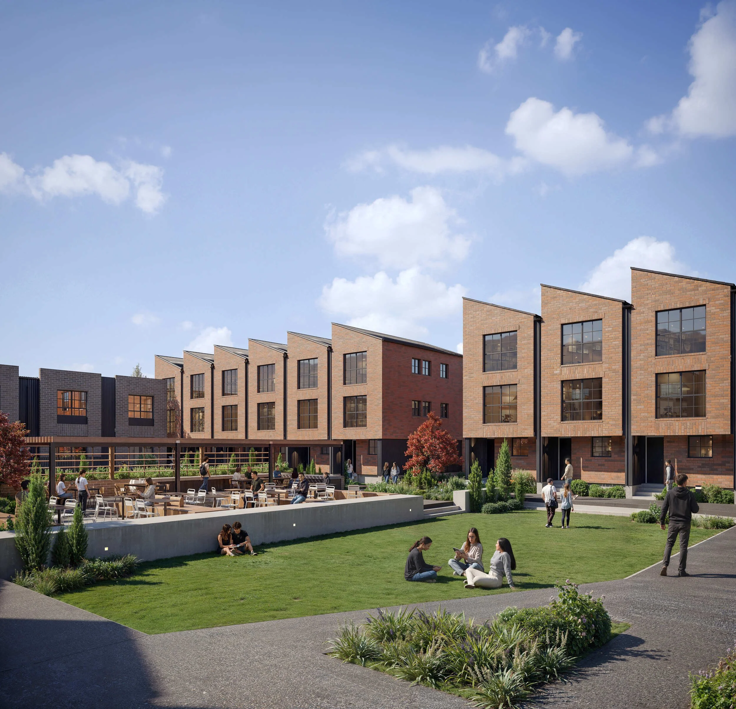 People sitting and walking in a grassy courtyard area with a modern brick apartment building in the background under a blue sky with clouds.