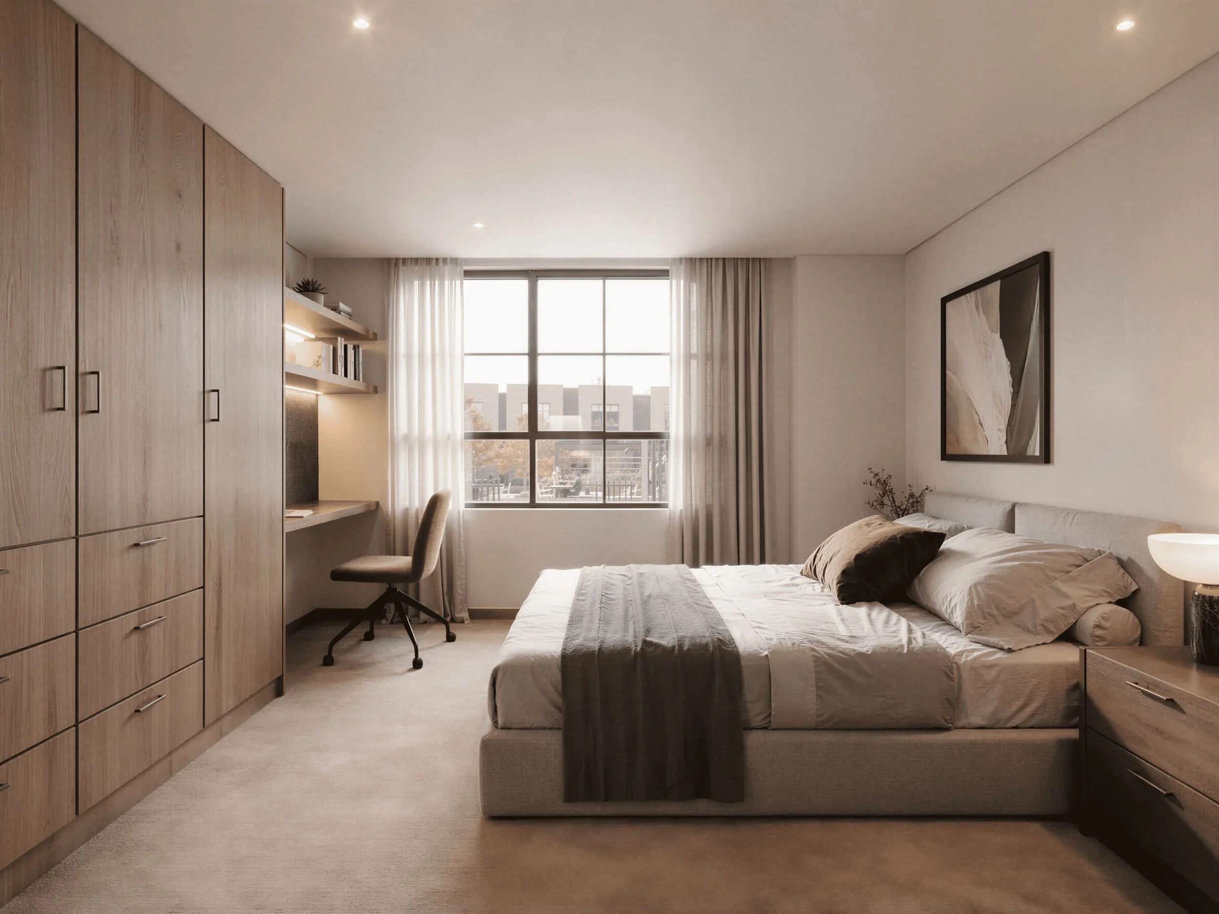 A modern bedroom with beige walls and carpeted floor, large window with white curtains, wooden wardrobe, small desk with shelving, bed with beige and brown bedding, framed artwork on the wall, and a bedside table.