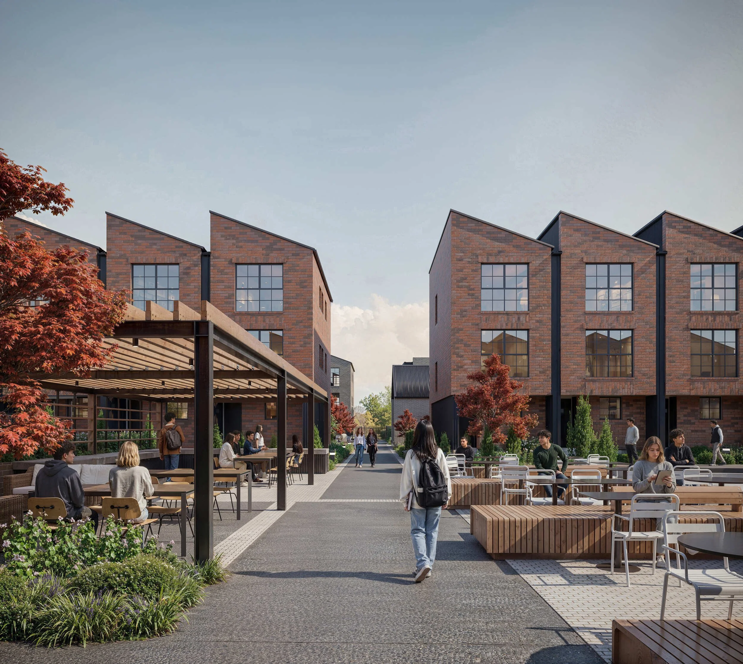 Students socializing and studying in an outdoor courtyard surrounded by modern brick buildings with large windows and trees with fall foliage.