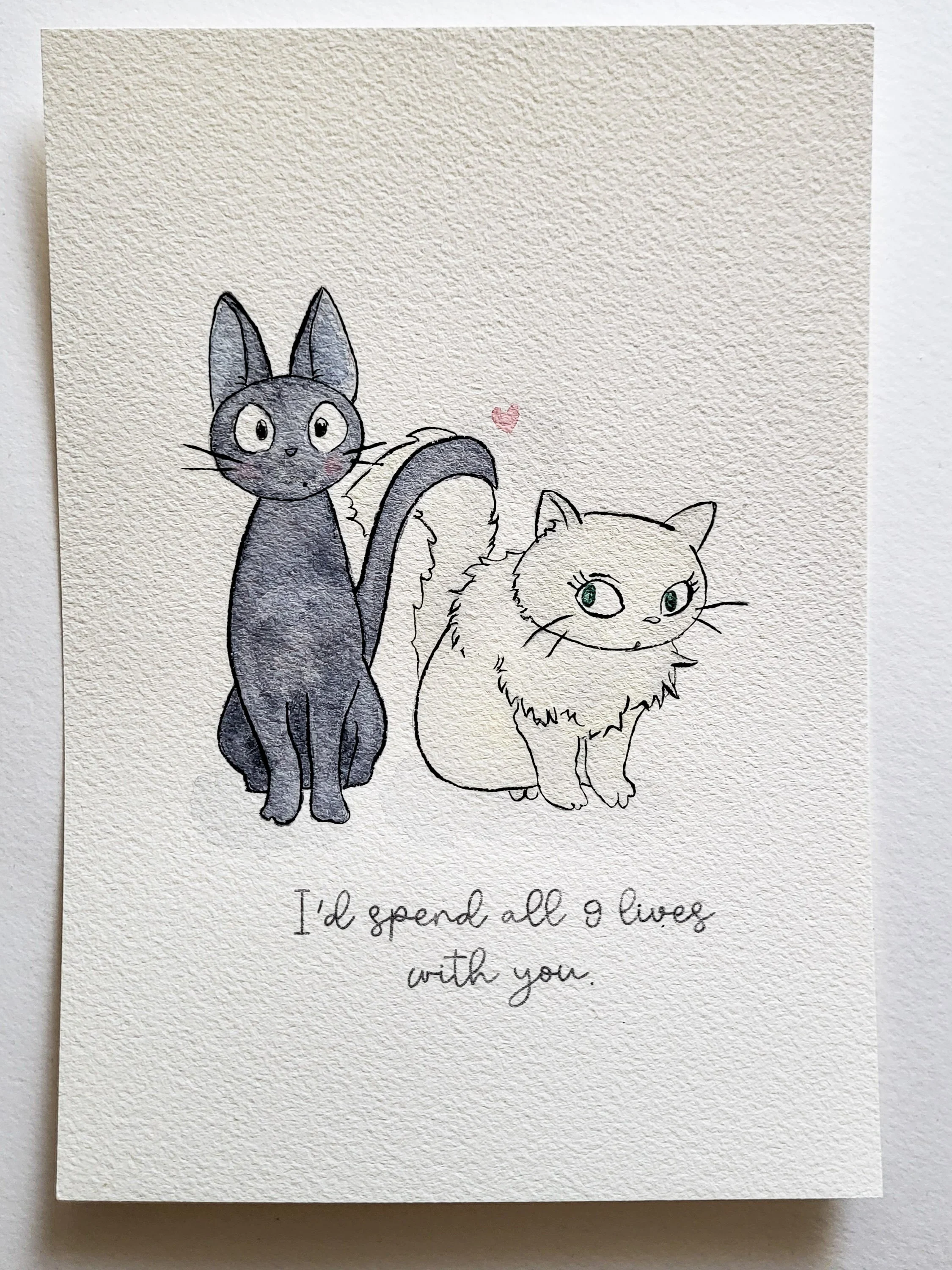 Une illustration de deux chats, l'un noir et l'autre blanc, avec un petit cœur rose au-dessus de leur queue. En dessous, une phrase écrit à la main dit : "I'd spend all 9 lives with you."