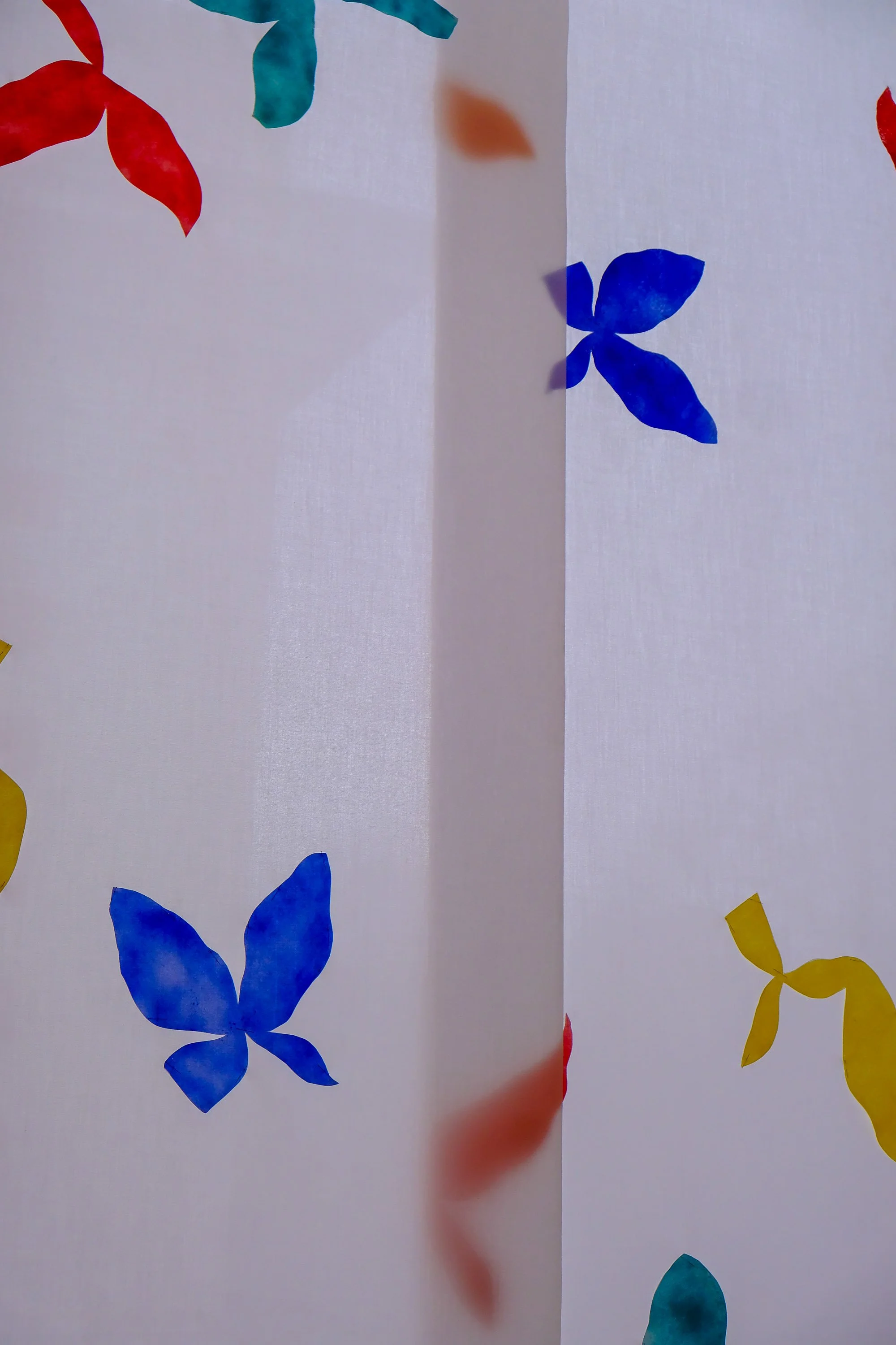 Papier blanc avec des formes de papillons et de feuilles colorées en rouge, bleu, vert et jaune.
