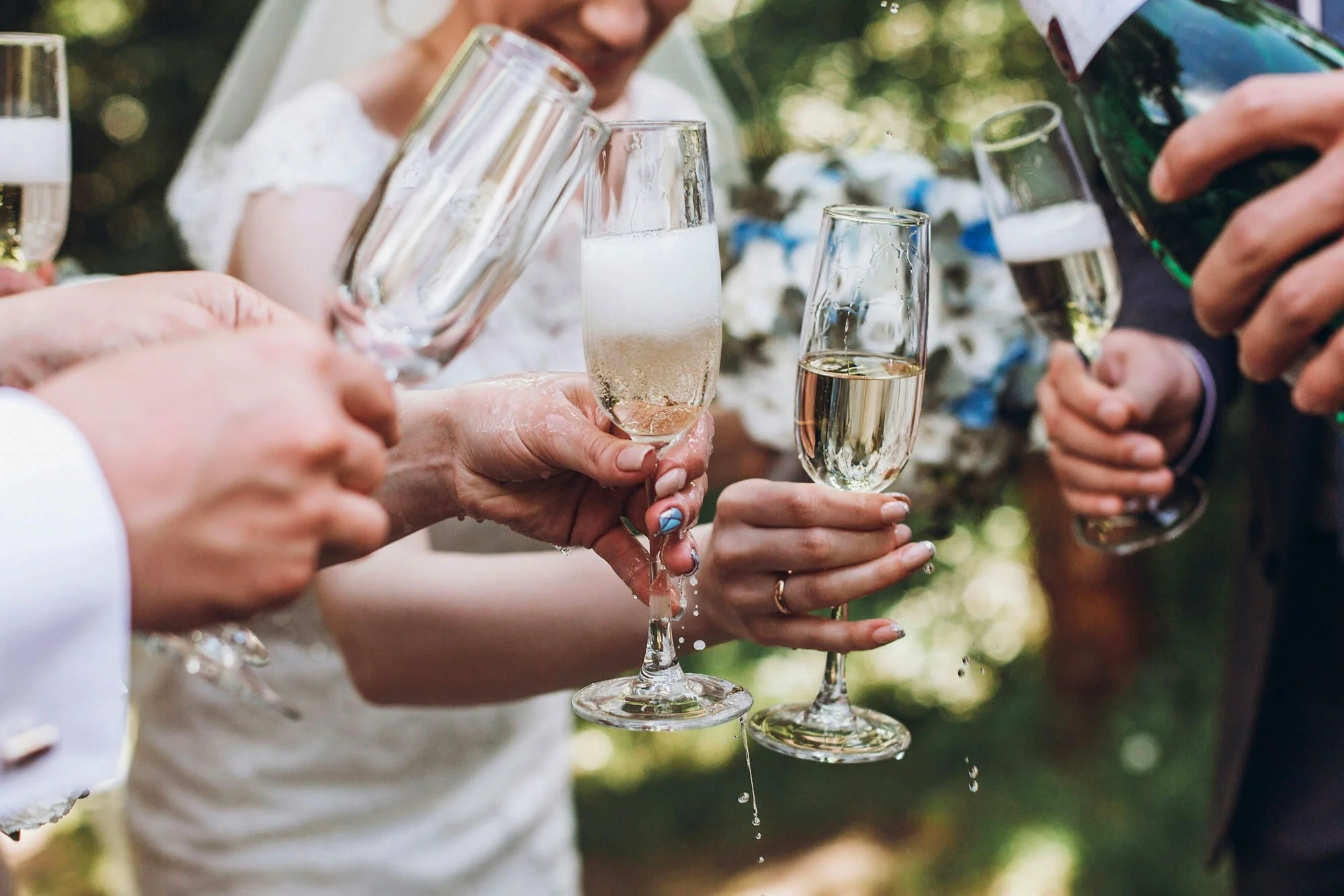 Groupe de personnes à une célébration levant des verres de champagne pour porter un toast lors d'une fête en plein air.
