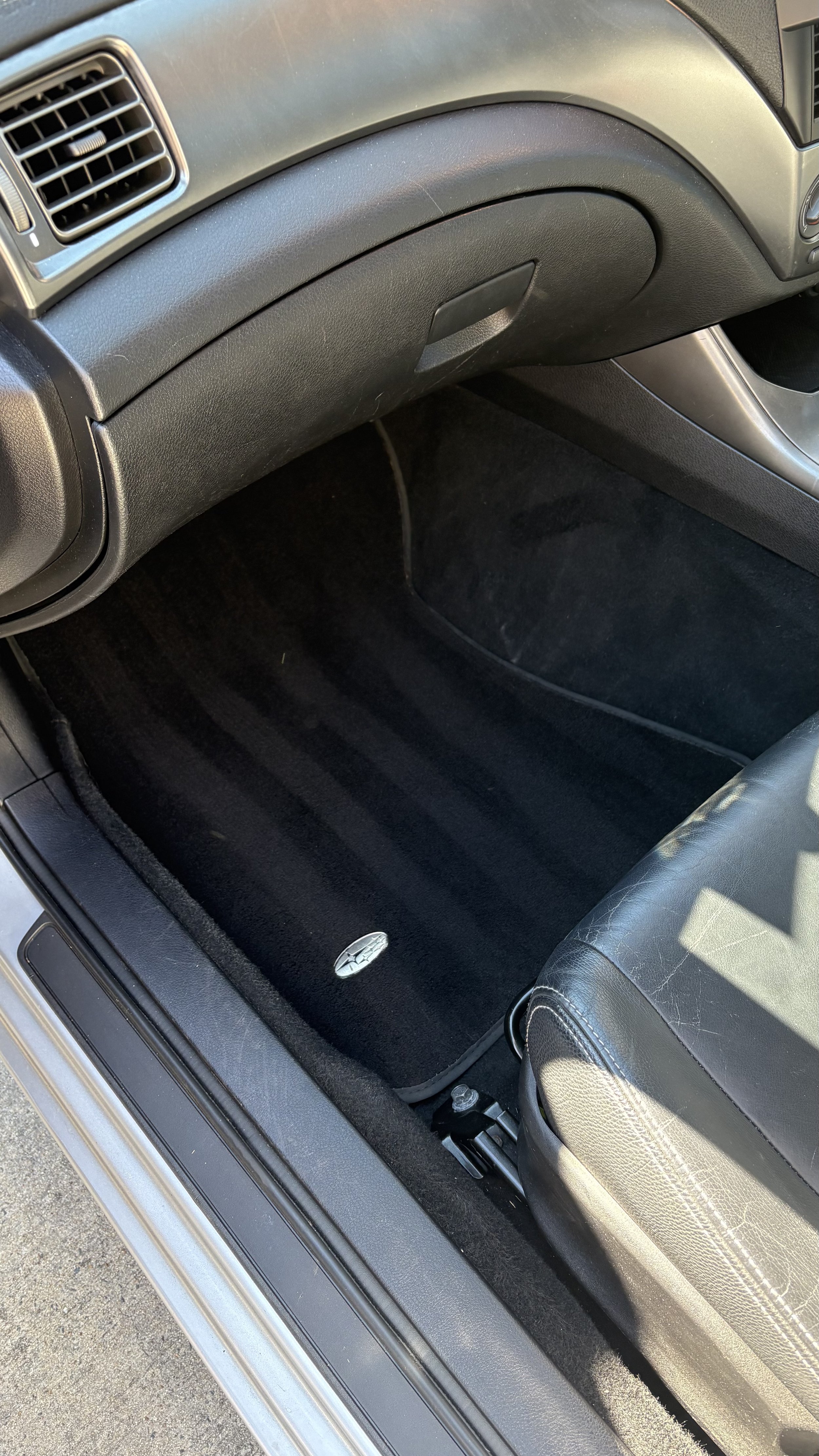 Interior of a car showing the passenger side, including the seat, floor mat, and dashboard air vent.
