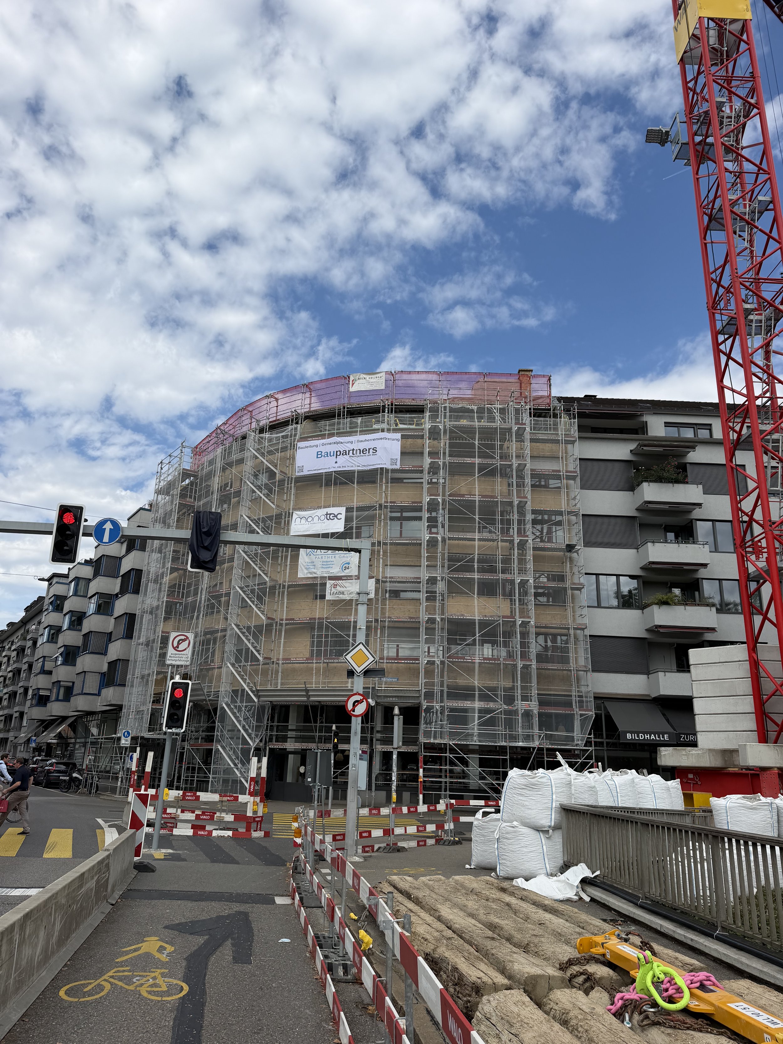 Bauarbeiten an einem Gebäude, Gerüste, Absperrungen, Baustoffe, Wolken am Himmel, Ampel, Fahrradweg