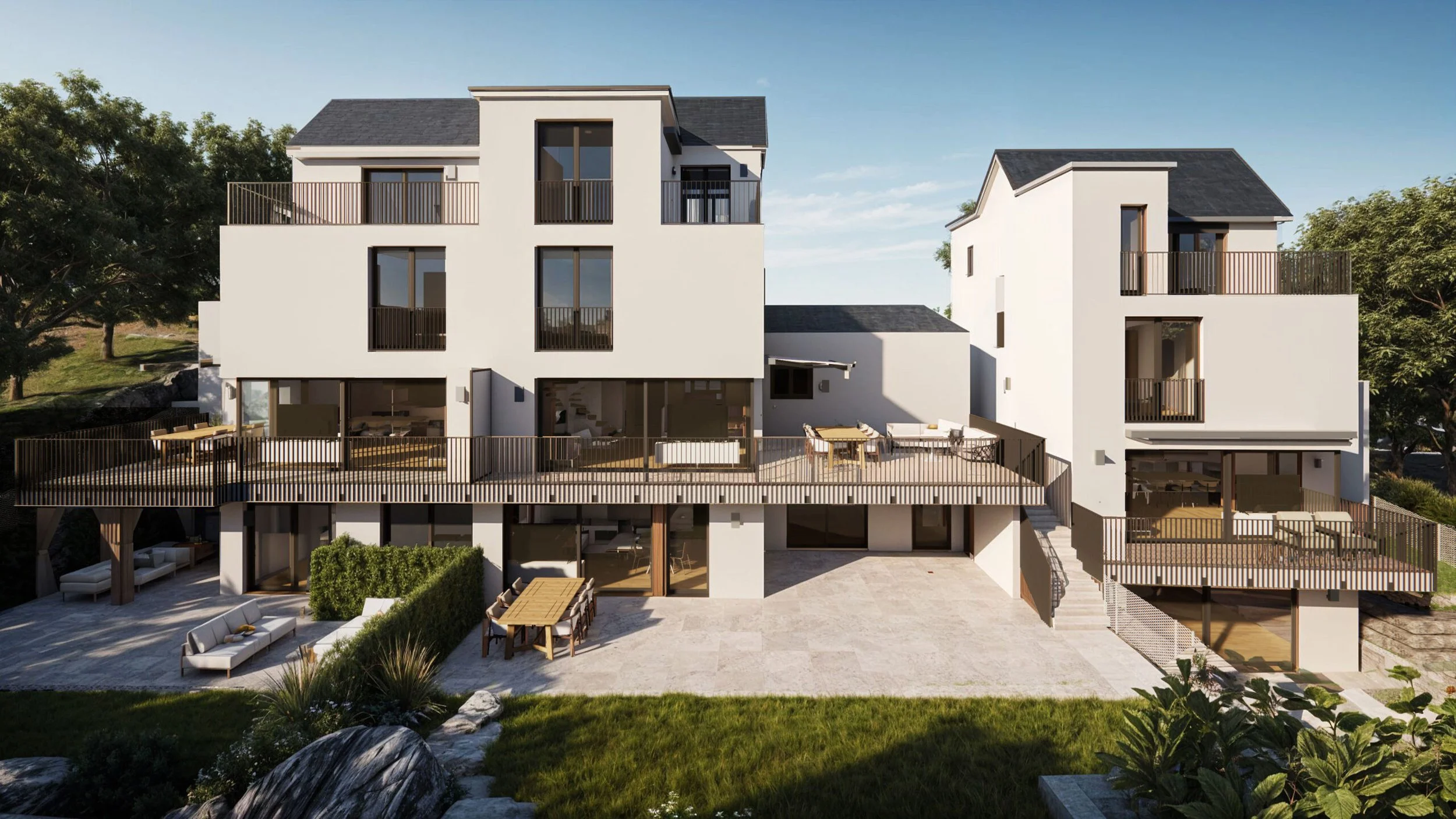 Moderne weiße Mehrfamilienhäuser mit Balkonen und Terrasse im Garten, umgeben von Bäumen, Blick auf den blauen Himmel.