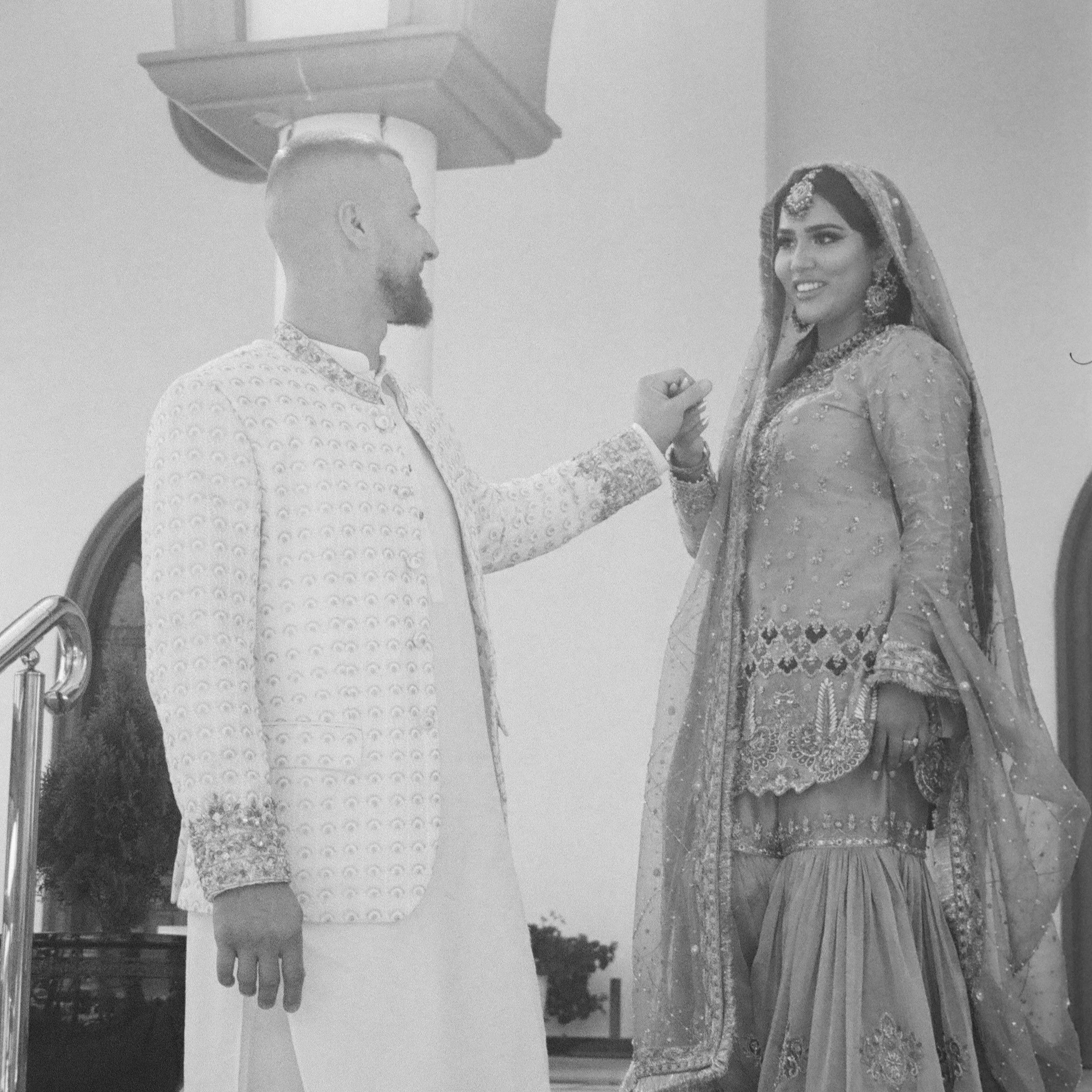 A newlywed couple exchanging rings during their wedding ceremony, with the groom on the left and the bride on the right, both dressed in traditional wedding attire.