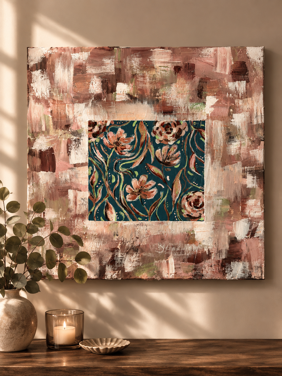 Abstract wall art with pink, white, and brown brushstrokes surrounding a floral pattern with pink flowers and green leaves on a dark blue background, mounted on a beige wall.