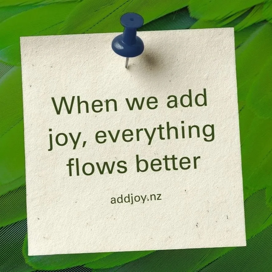 A white paper with the quote "When we add joy, everything flows better" on green feathers. The source "www.addjoy.nz" is printed at the bottom.