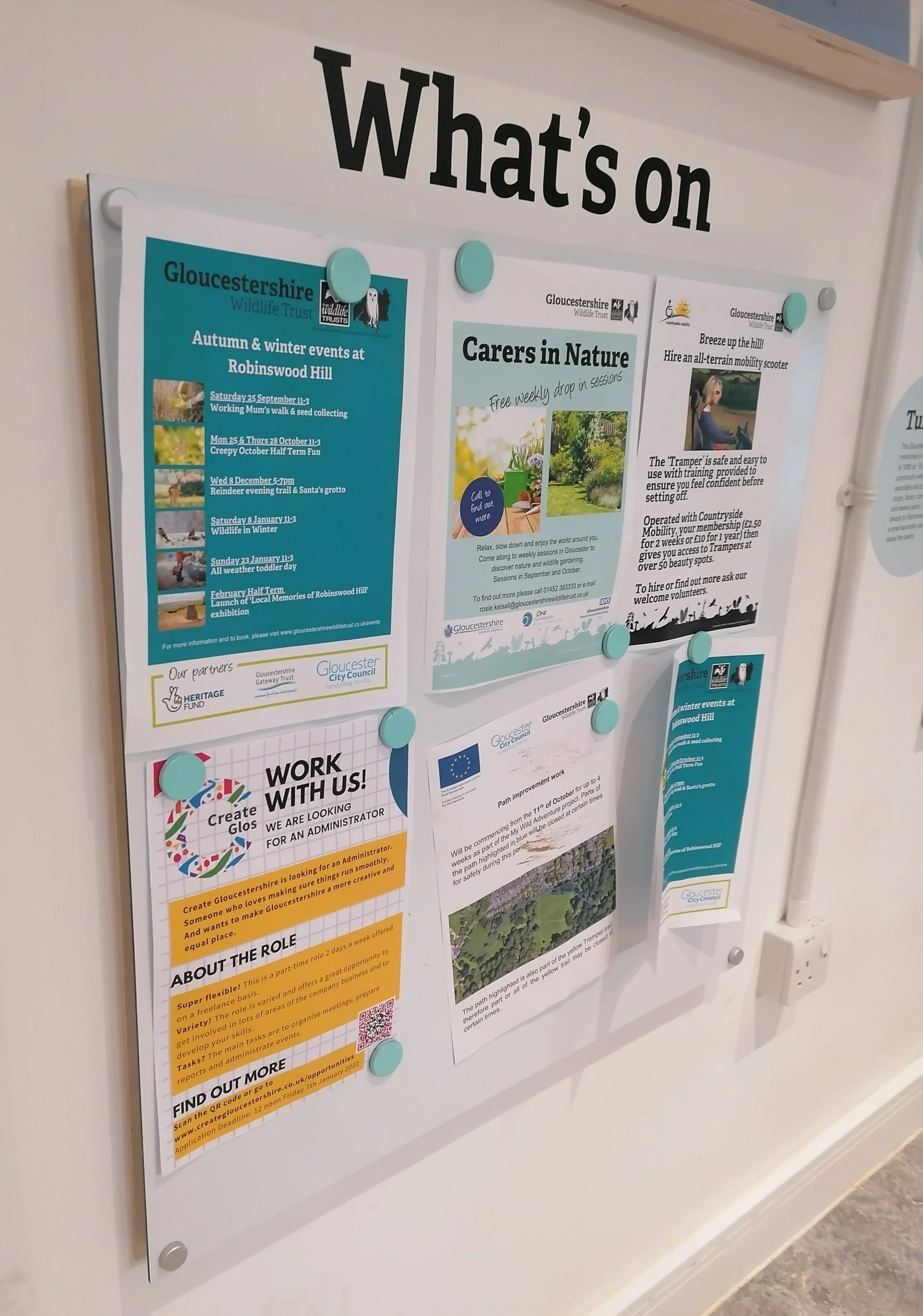 “What’s on” noticeboard with posters including Carers in Nature and a Create Glos “Work with us” recruitment flyer.