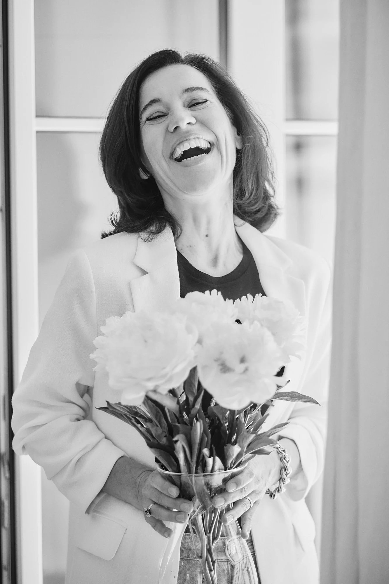 Eine Frau hält einen Blumenstrauß mit großen, offenen Blüten, lächelt und wirkt glücklich.
