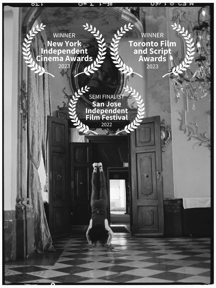 Ein Kind macht eine Handstand-Position an einem historischen, kunstvoll dekorierten Raum, mit Auszeichnungen für verschiedene Filmfestivals im oberen Bereich