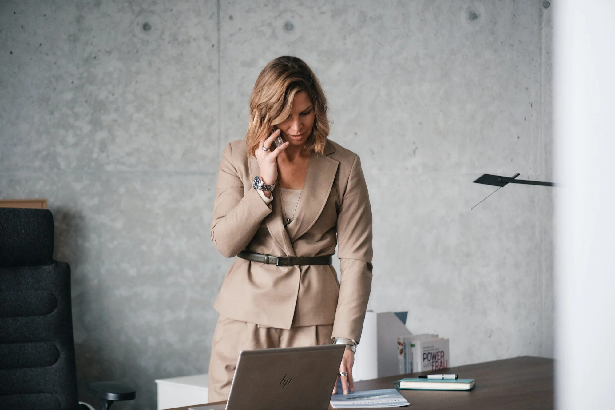 Eine Frau in Business-Kleidung, die an einem Schreibtisch arbeitet, während sie telefoniert.