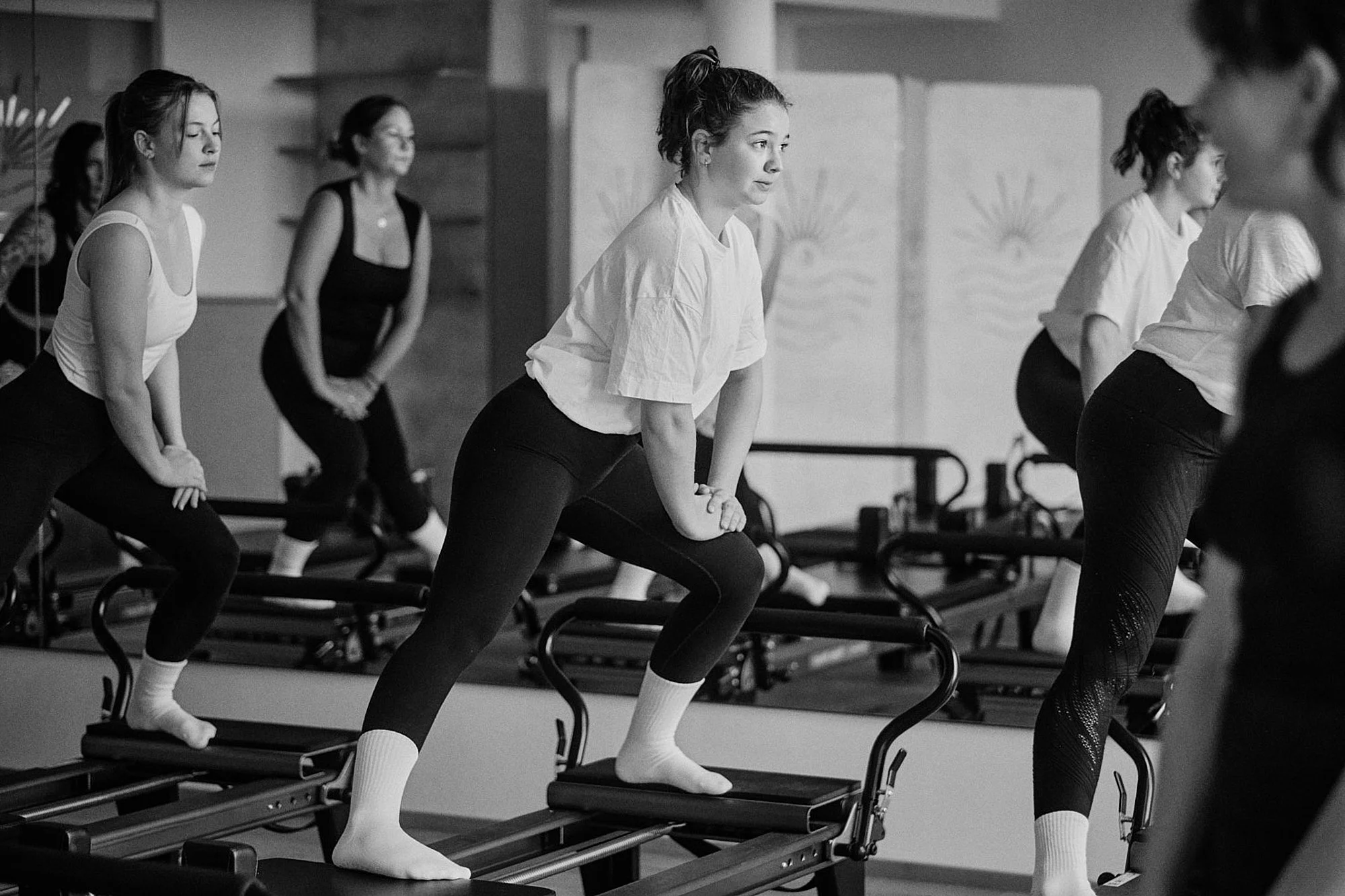 Menschen beim Gruppen-Workout auf Trampolinen im Fitnessstudio, alle in aktiver Haltung, im Schwarz-Weiß Foto.