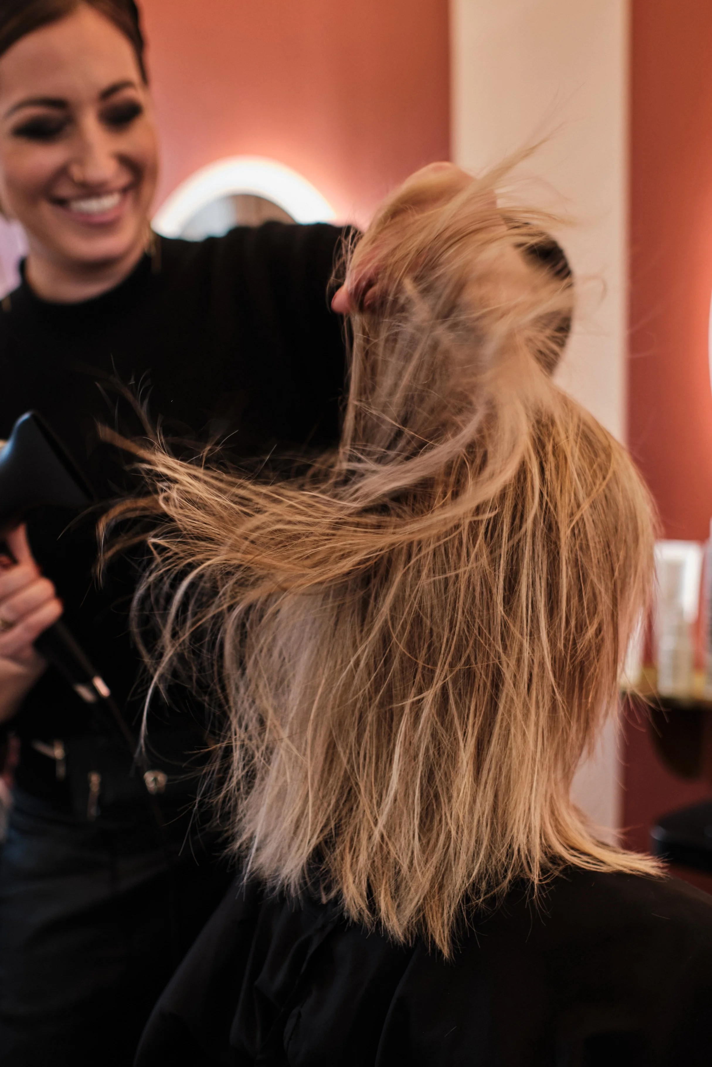 Friseurin schneidet und stylt eine langhaarige Blondine in einem Salon.