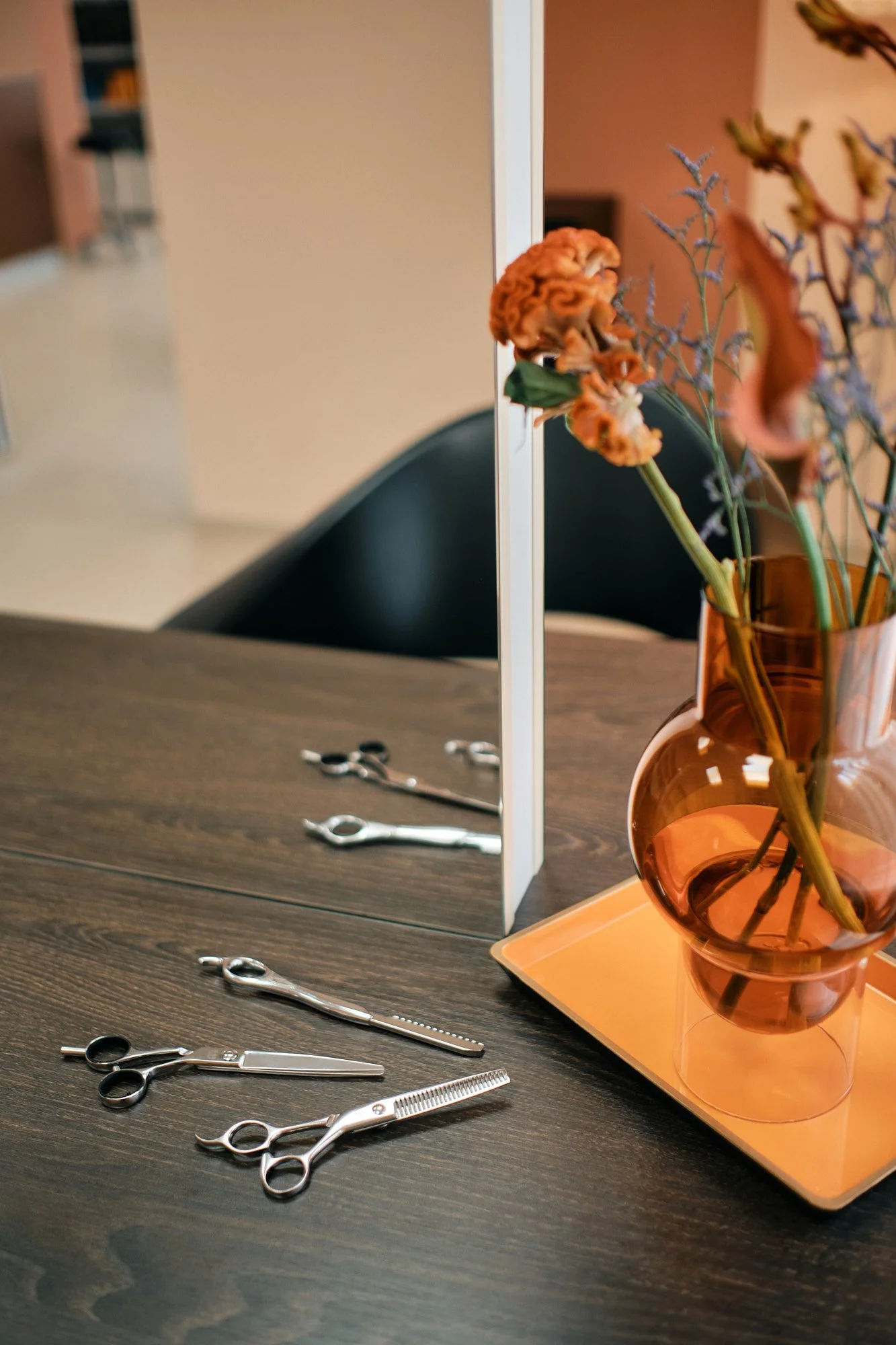Friseursalon-Setup mit Haarscheren, Kamm, Spiegel, Blumenstrauß in einer Vase auf einem Tisch.