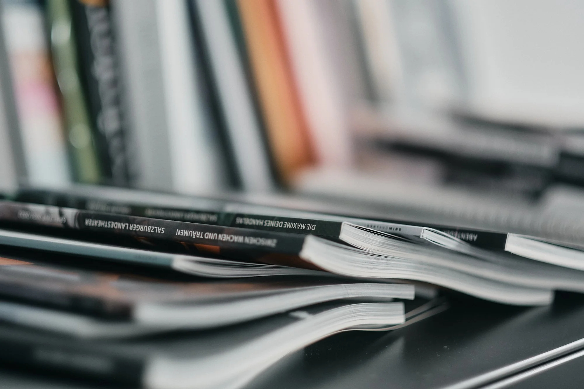 Näheaufnahme eines Stapels Zeitschriften oder Magazine, die auf einem Tisch liegen.