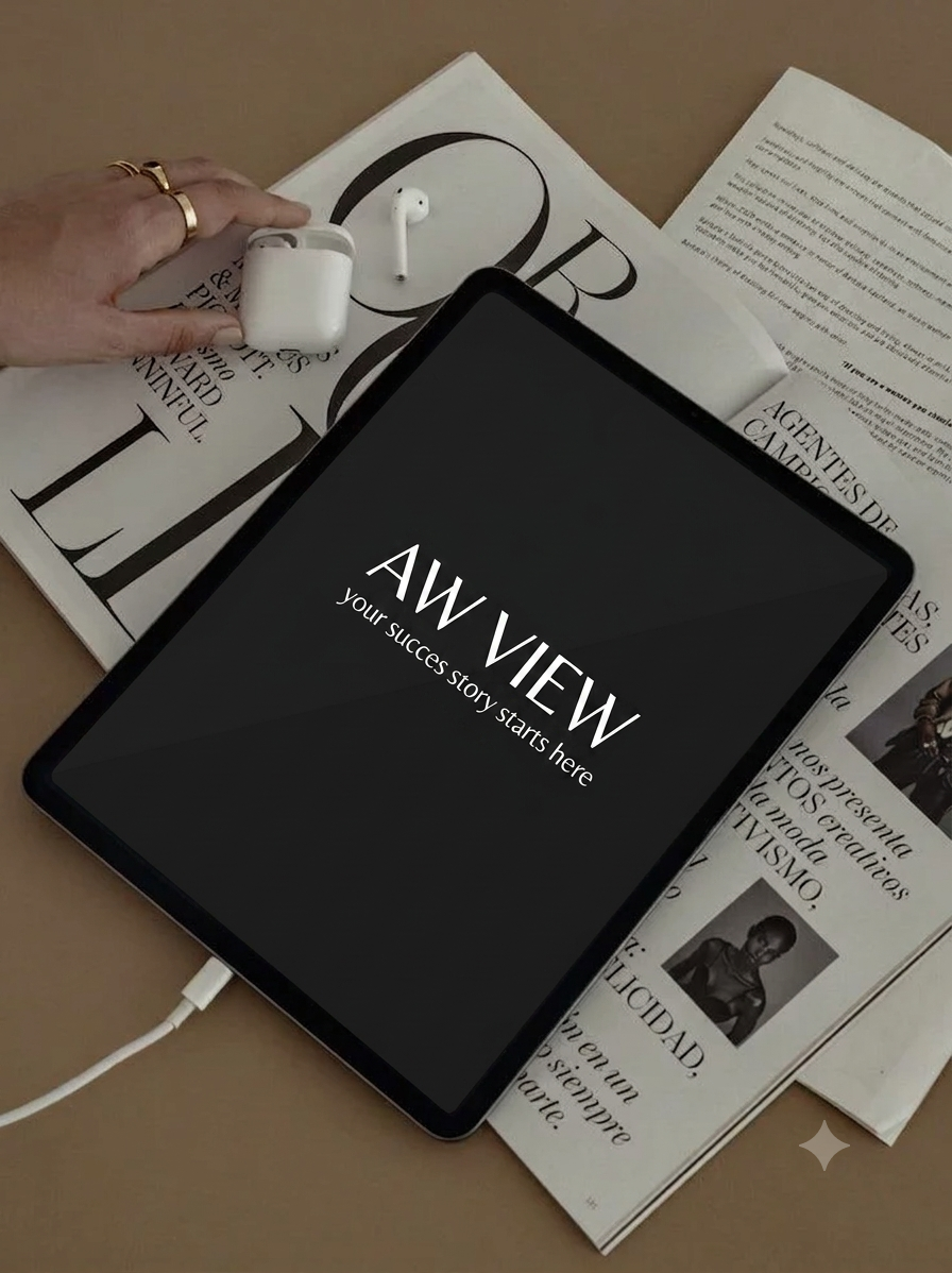 Tablet displaying 'AW VIEW your success story starts here' on a table with a magazine, a pair of wireless earbuds, and a charging case.