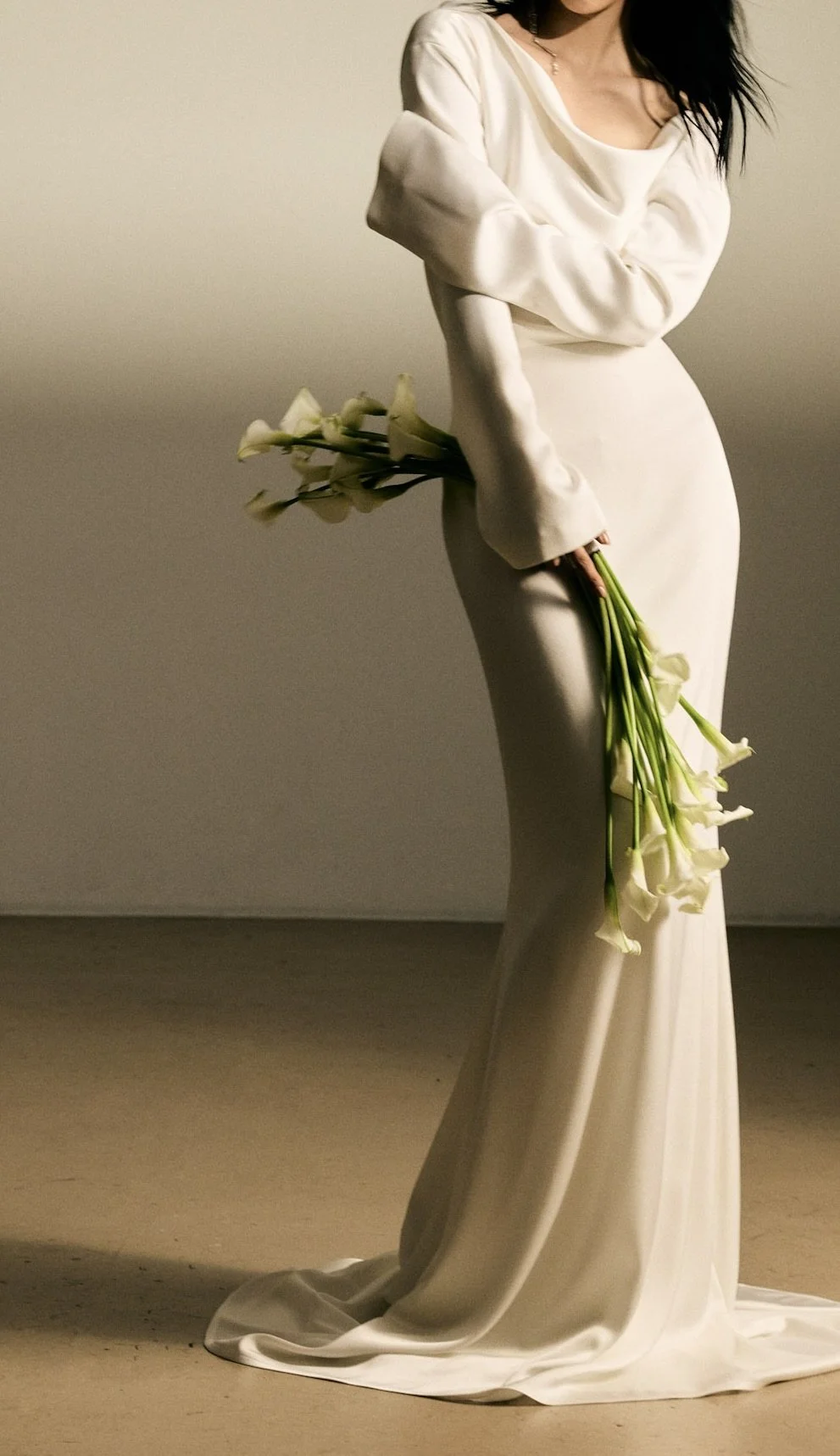 Woman in a long white gown holding a bouquet of white calla lilies