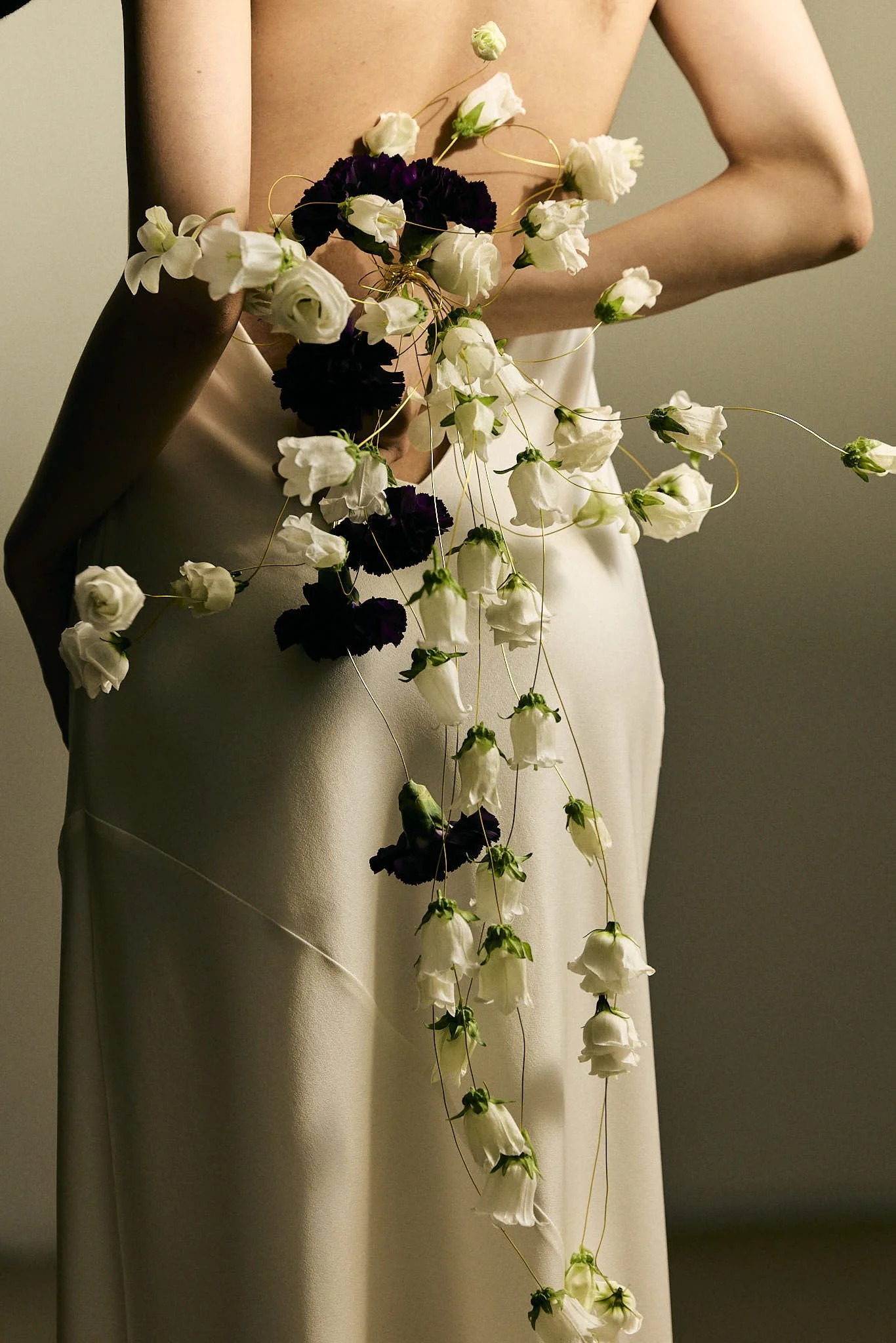 Person in a white dress adorned with cascading white and deep purple flowers