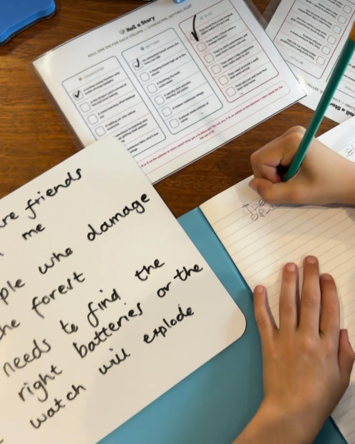 Close-up of a person writing in a notebook at a desk with school papers and handwritten notes visible.