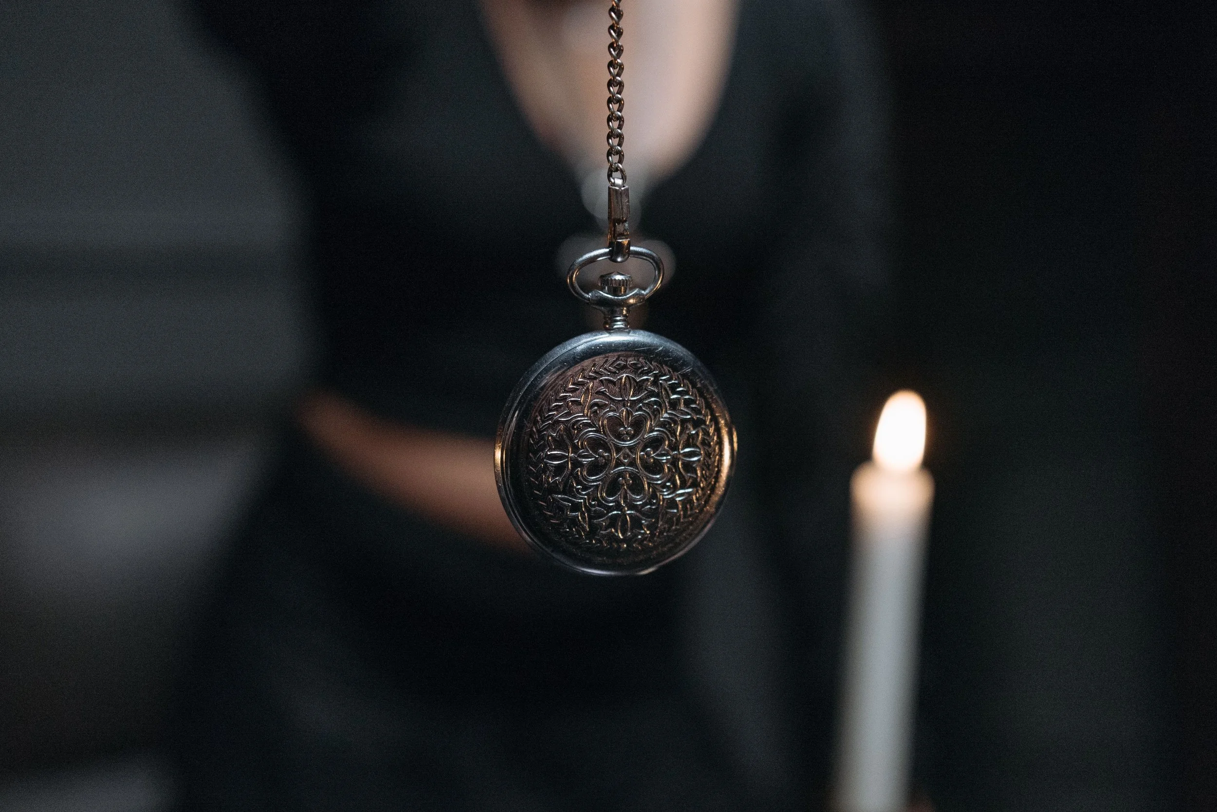 A pocket watch held in the foreground as if to hypnotize the viewer