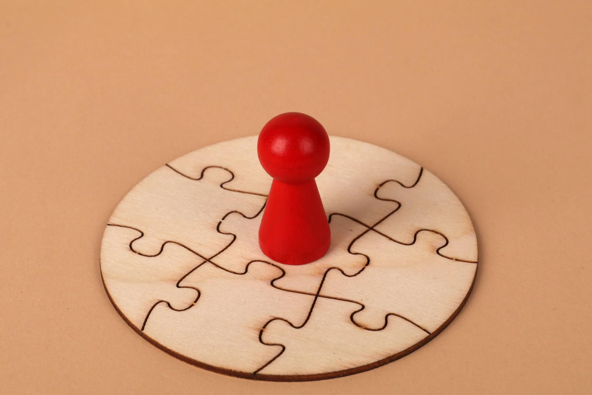 A small red board game piece on top of a completed puzzle