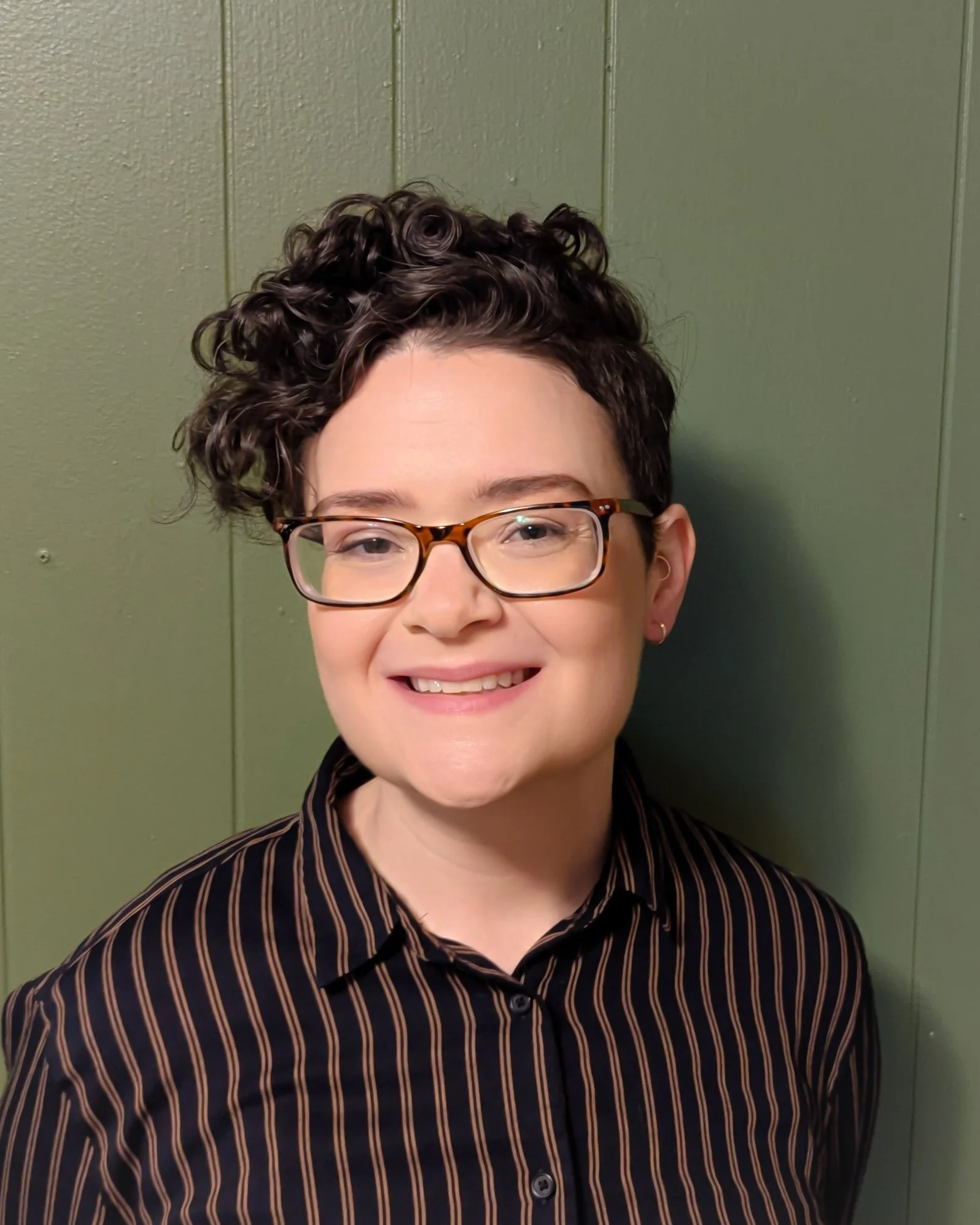Close-up photo of a smiling nonbinary person with short curly hair and glasses | Virtual therapy for ADHD in Massachusetts