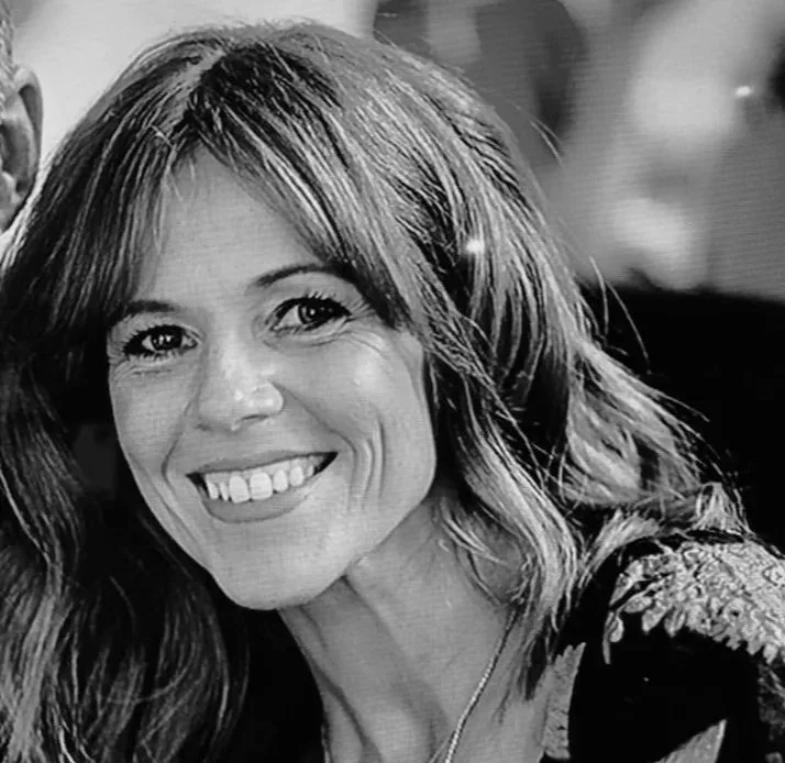Black and white close-up photo of a smiling woman with wavy hair