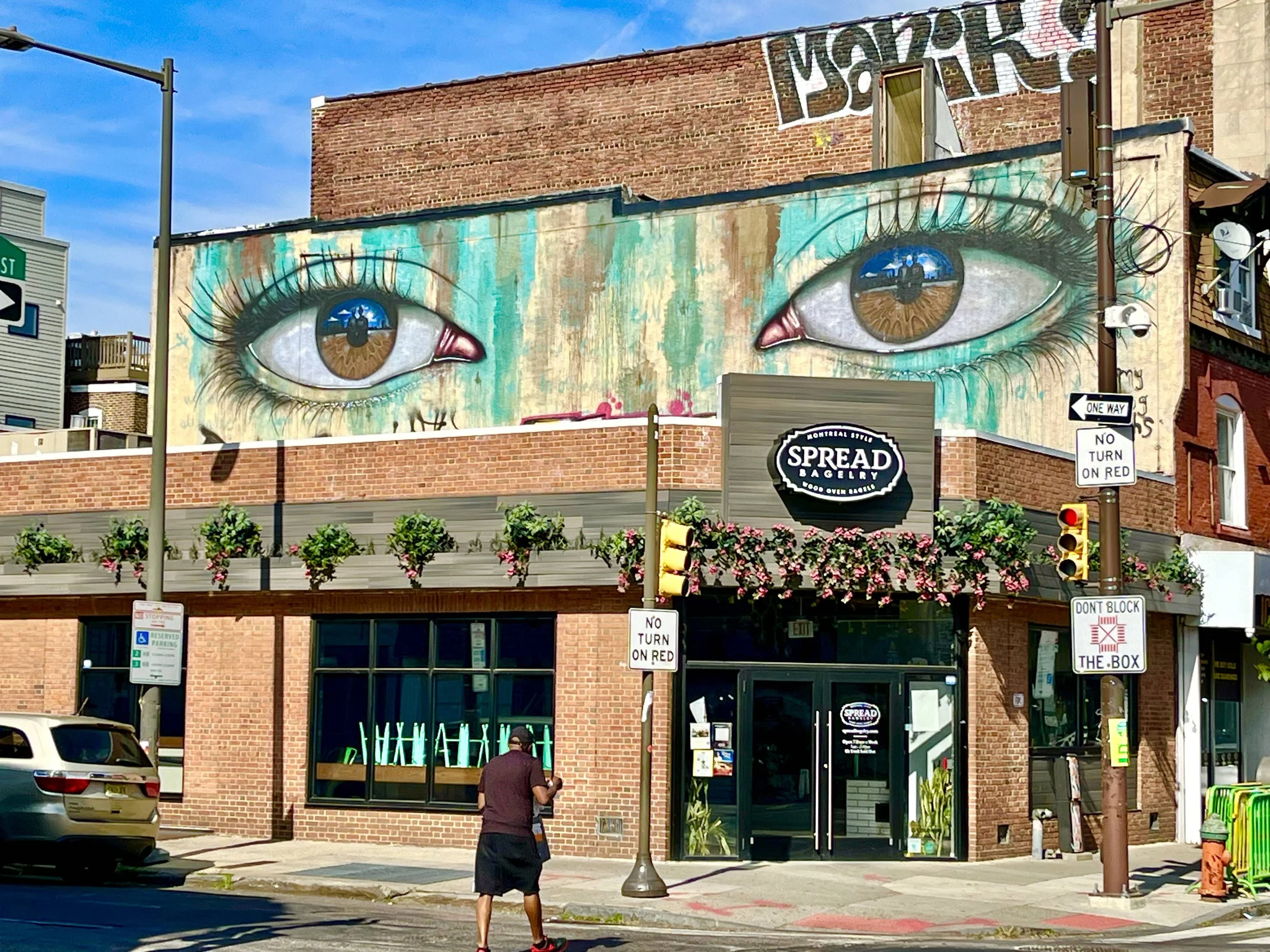 A large mural of realistic eyes with brown irises and long eyelashes painted on the side of a brick building.