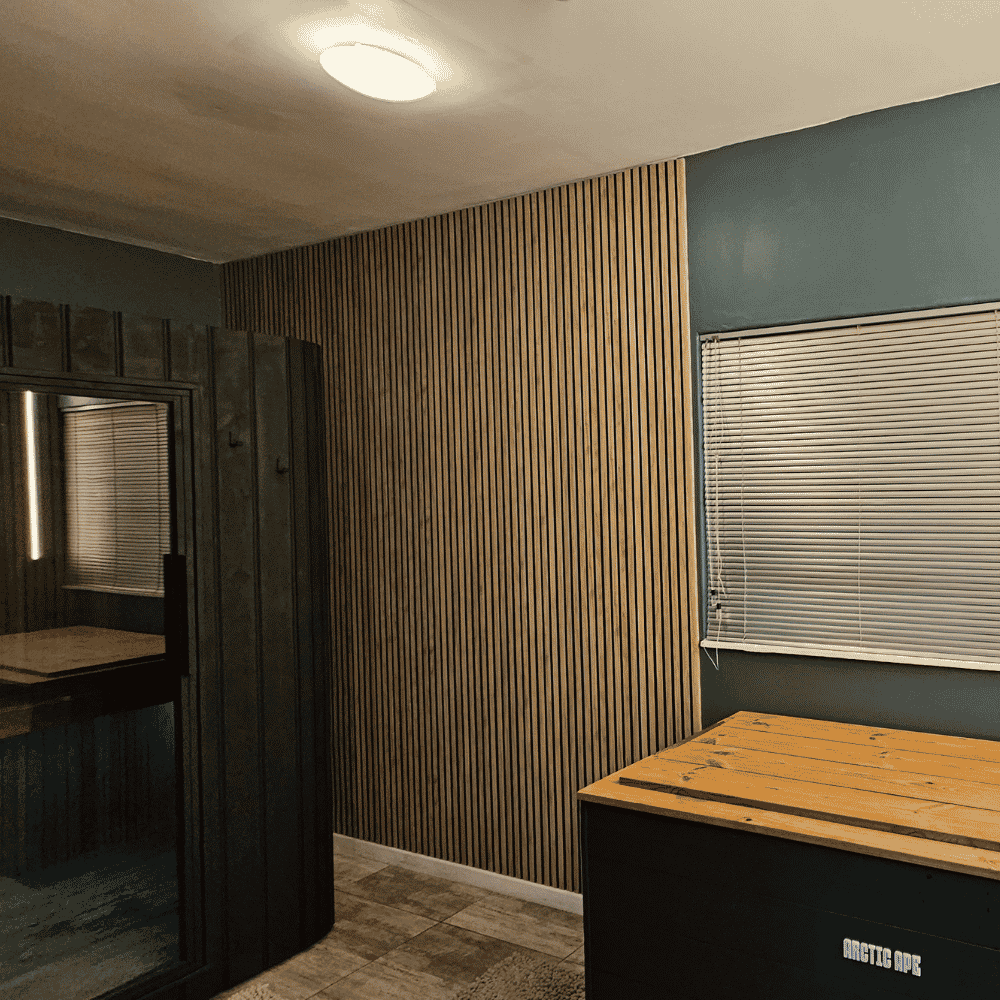 Interior of a room with wood and dark paneling walls, a window with closed blinds, a wooden table, and a ceiling light.