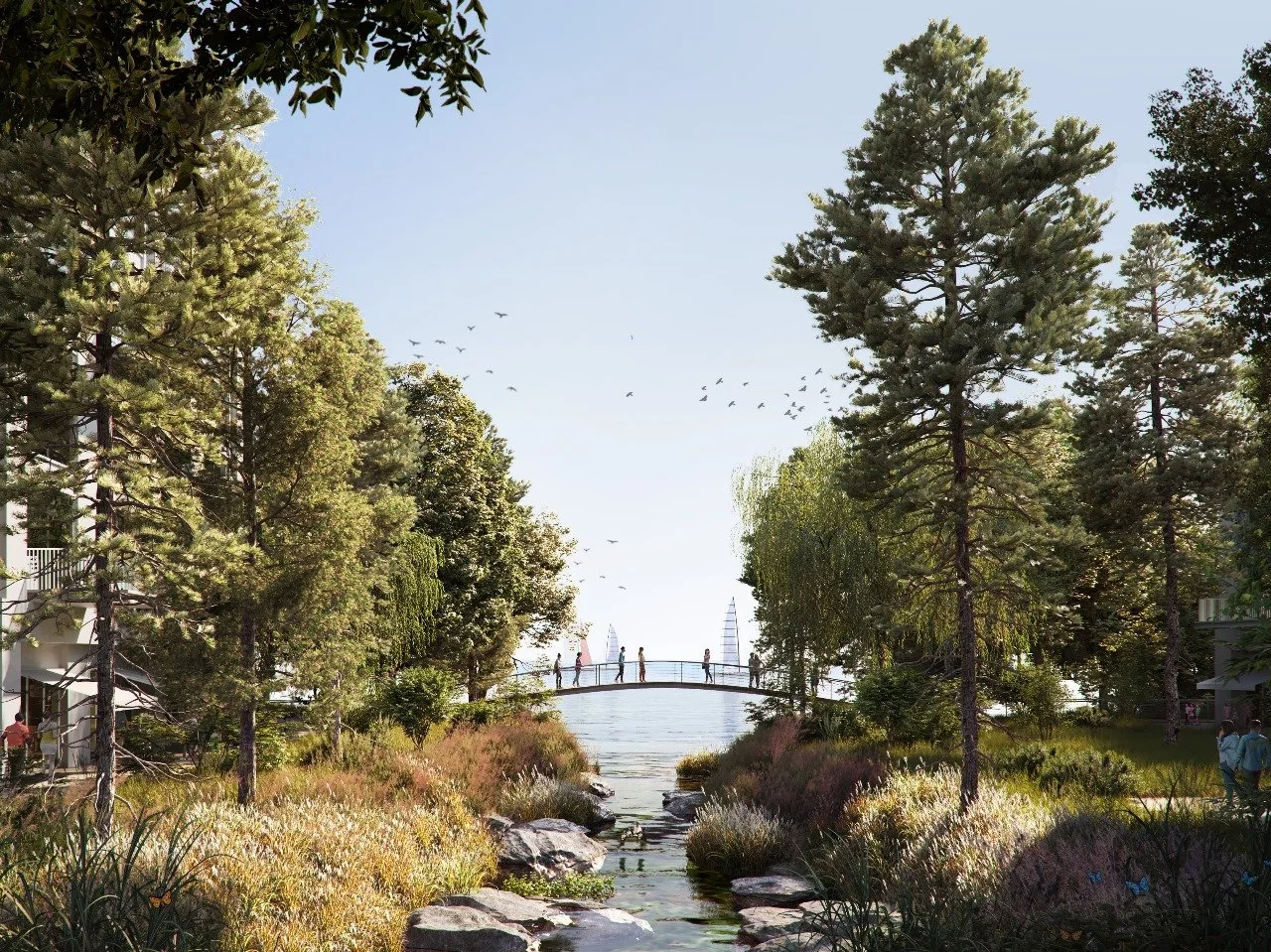 A scenic park in Larnaka -Cyprus scene with a small stream flowing through grassy and bushy areas, surrounded by tall trees. In the background, a bridge with people walking across it spans the stream. A flock of birds is flying in the clear blue sky.