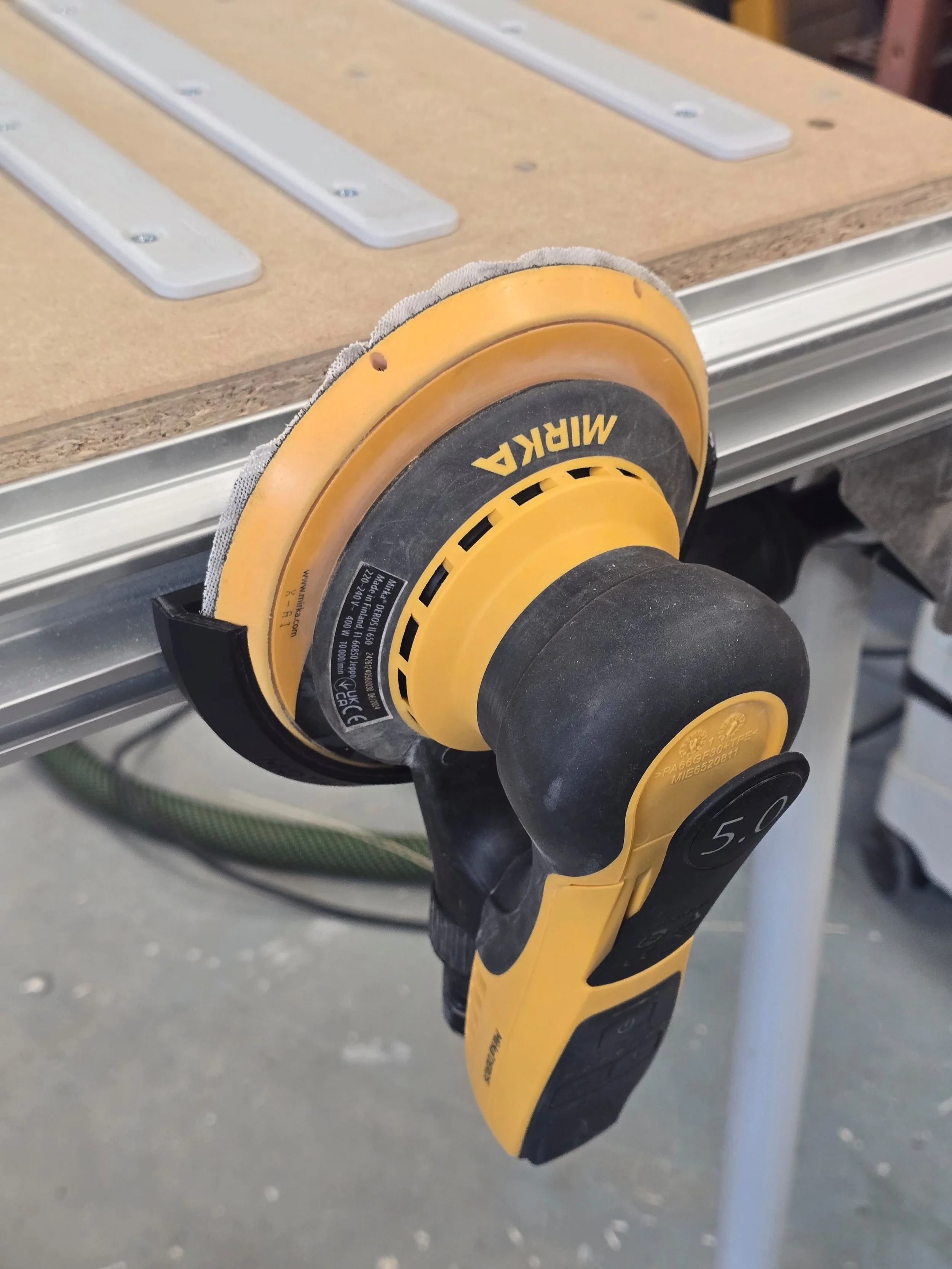 A Mirka DEROS 650 sander held in the 150mm sander mount, fitted to an MFT table's T-track