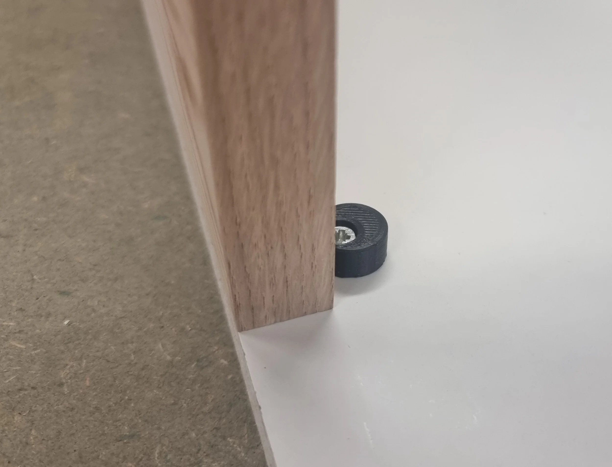 Close-up of the black door stop installed where a wood door meets a white cabinet surface