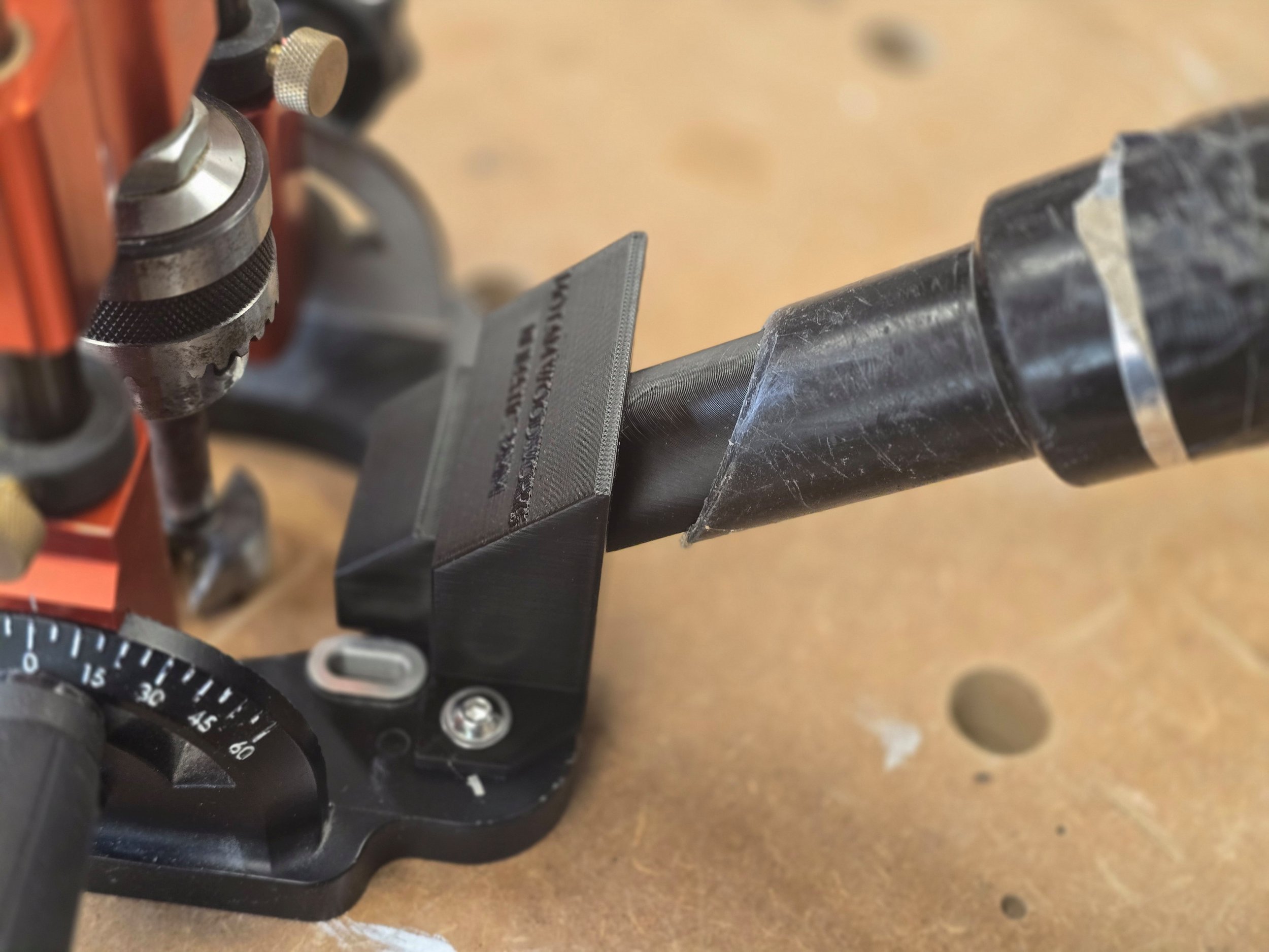 The dust adaptor mounted on a UJK Drill Guide with a Numatic vacuum hose connected