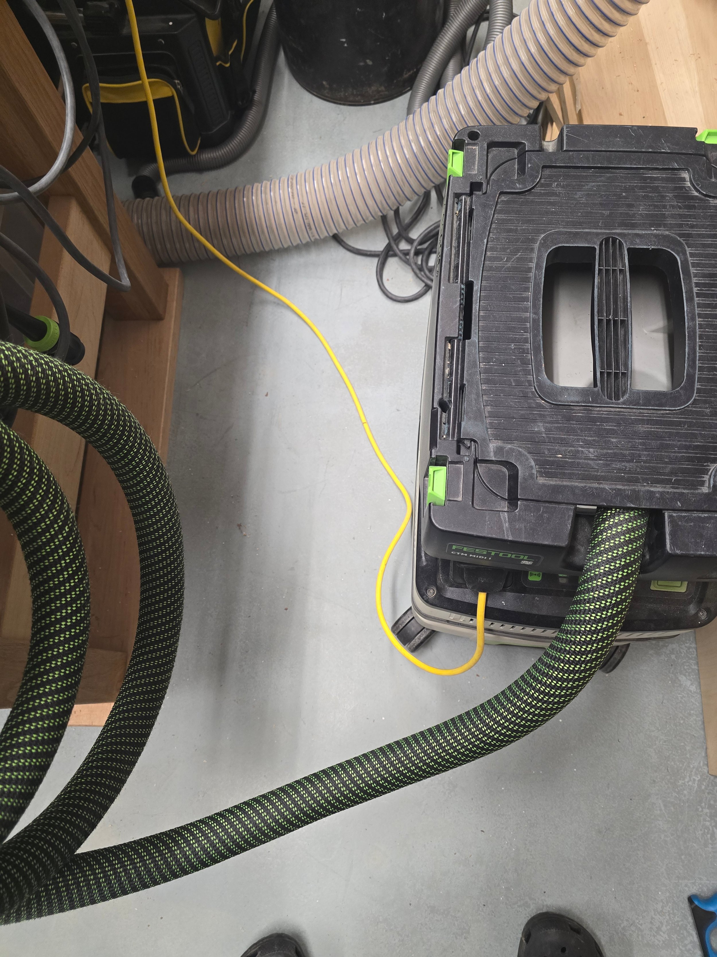 A Festool CTM MIDI dust extractor on the floor with hoses and cables tidied up