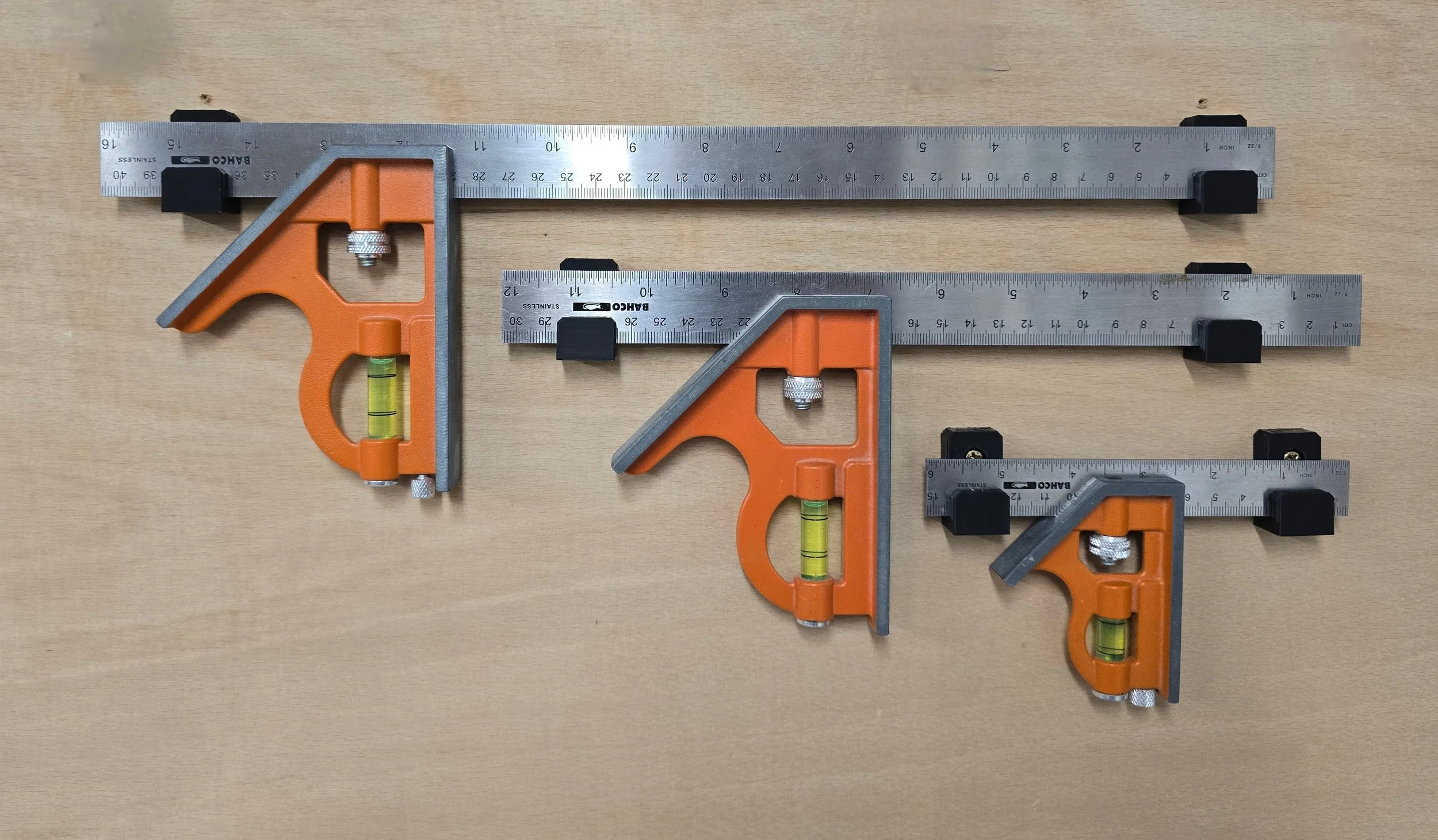 Three Bahco combination squares of decreasing size, each held by a pair of wall mount brackets, laid flat on a workbench