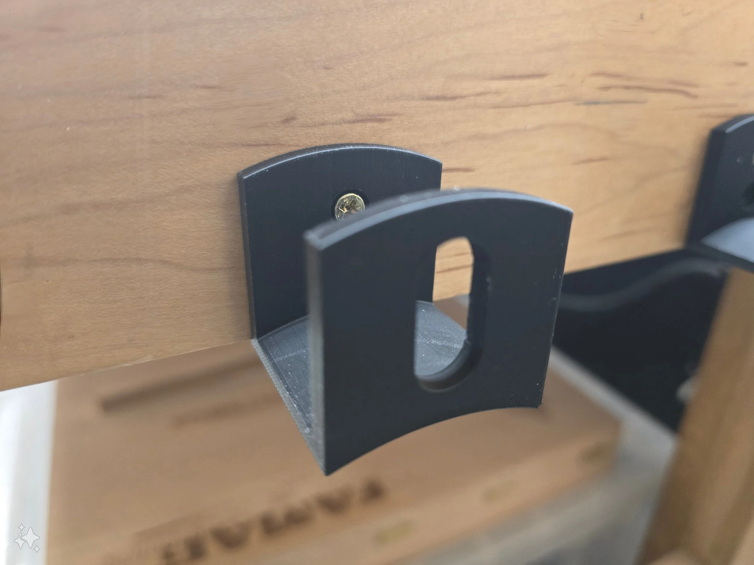 Close-up of a single empty cable wall hook, showing the oval cable slot and mounting screw hole