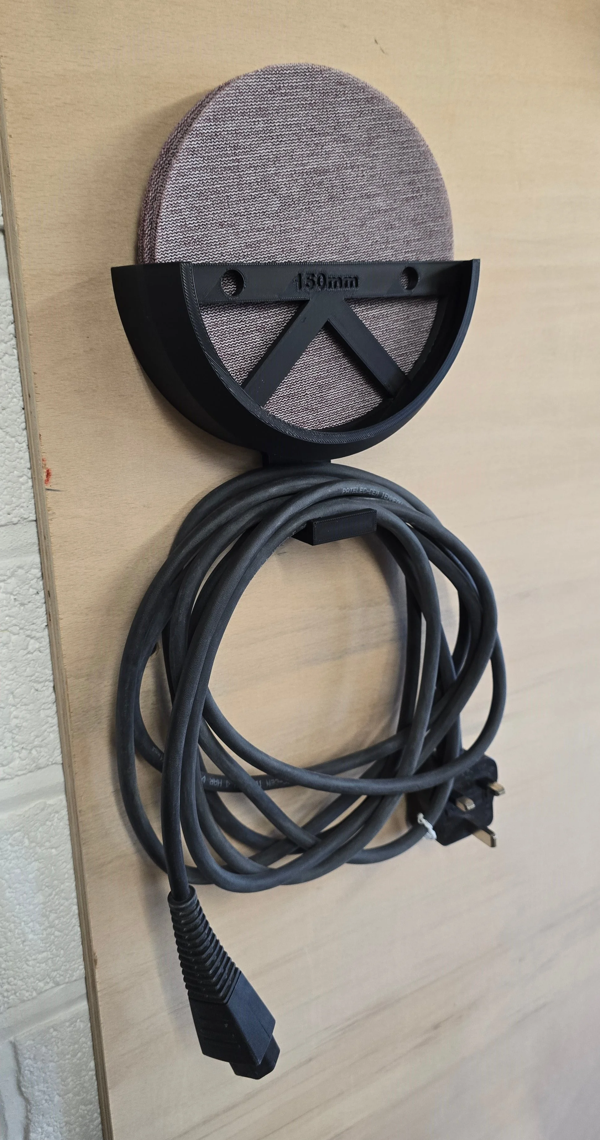 The 150mm bracket holding a stack of sanding discs, with the sander's mains cable coiled on the integrated cable hook below