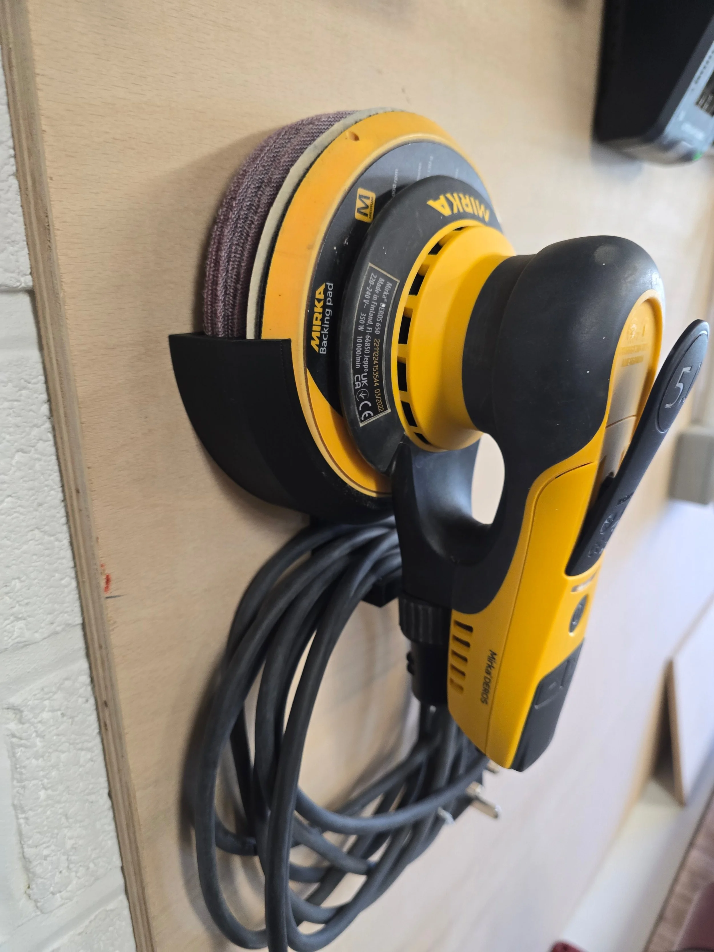 A Mirka DEROS 650 sander held in the 150mm bracket, with its cable coiled on the hook below