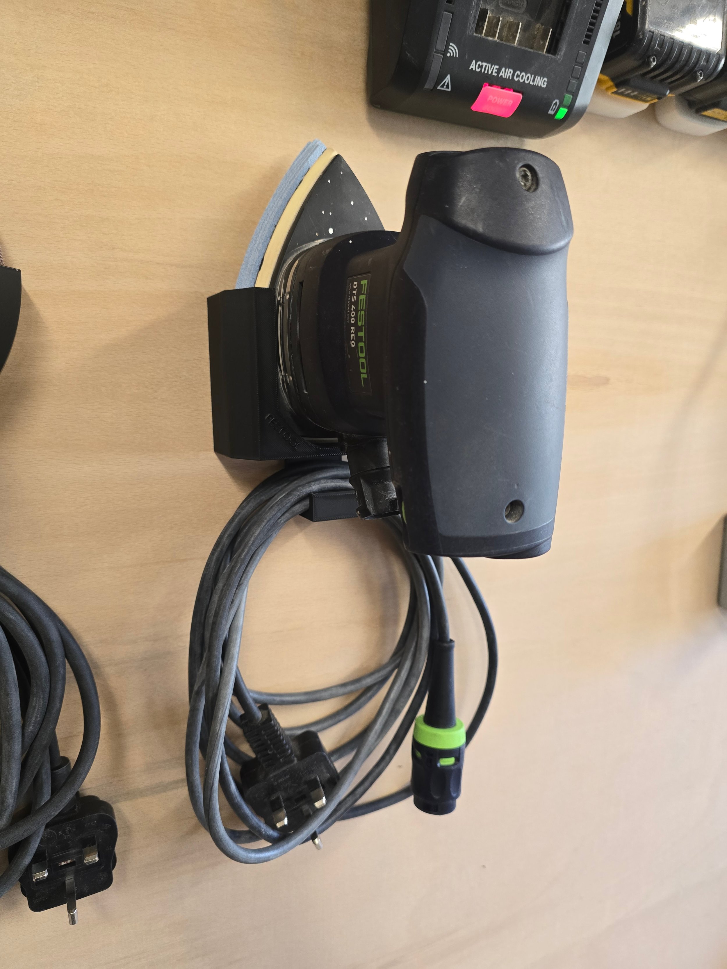 A Festool DTS 400 REQ sander held in its bracket, with its power and hose cables coiled on the hook below