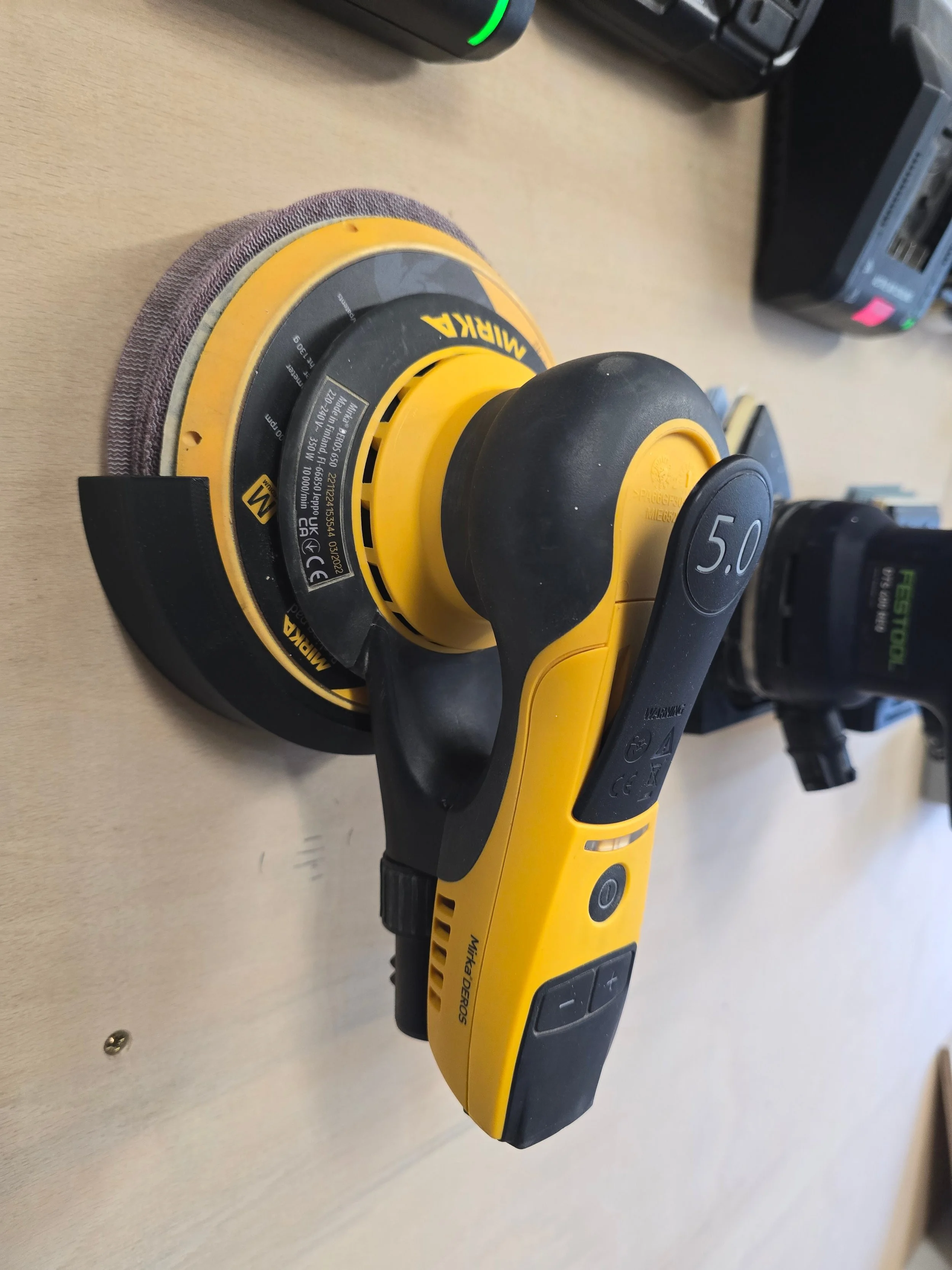 A Mirka DEROS 650 sander held in the 150mm wall mount bracket