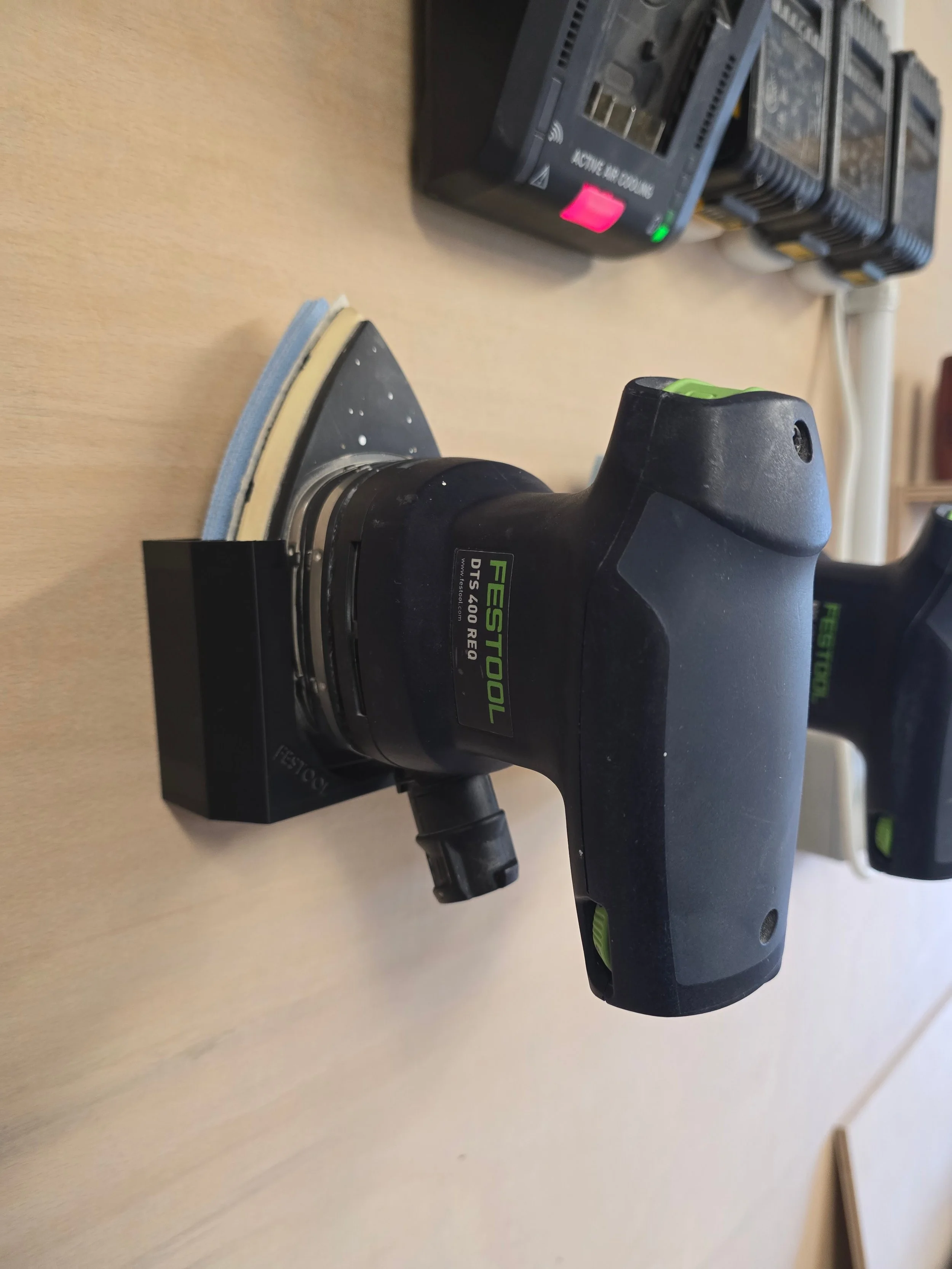 A Festool DTS 400 REQ sander held in its wall mount bracket