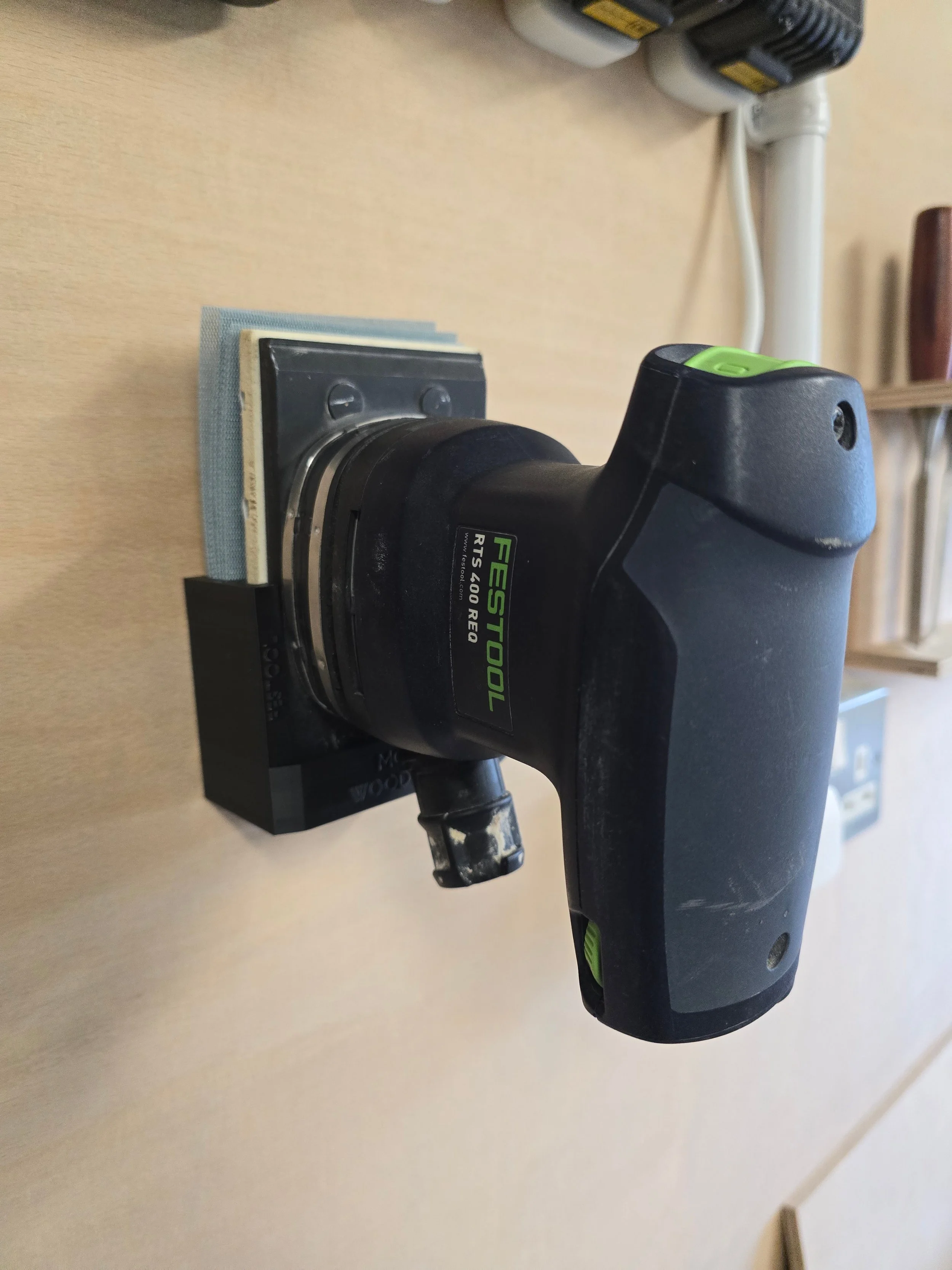 A Festool RTS 400 REQ sander held in its wall mount bracket