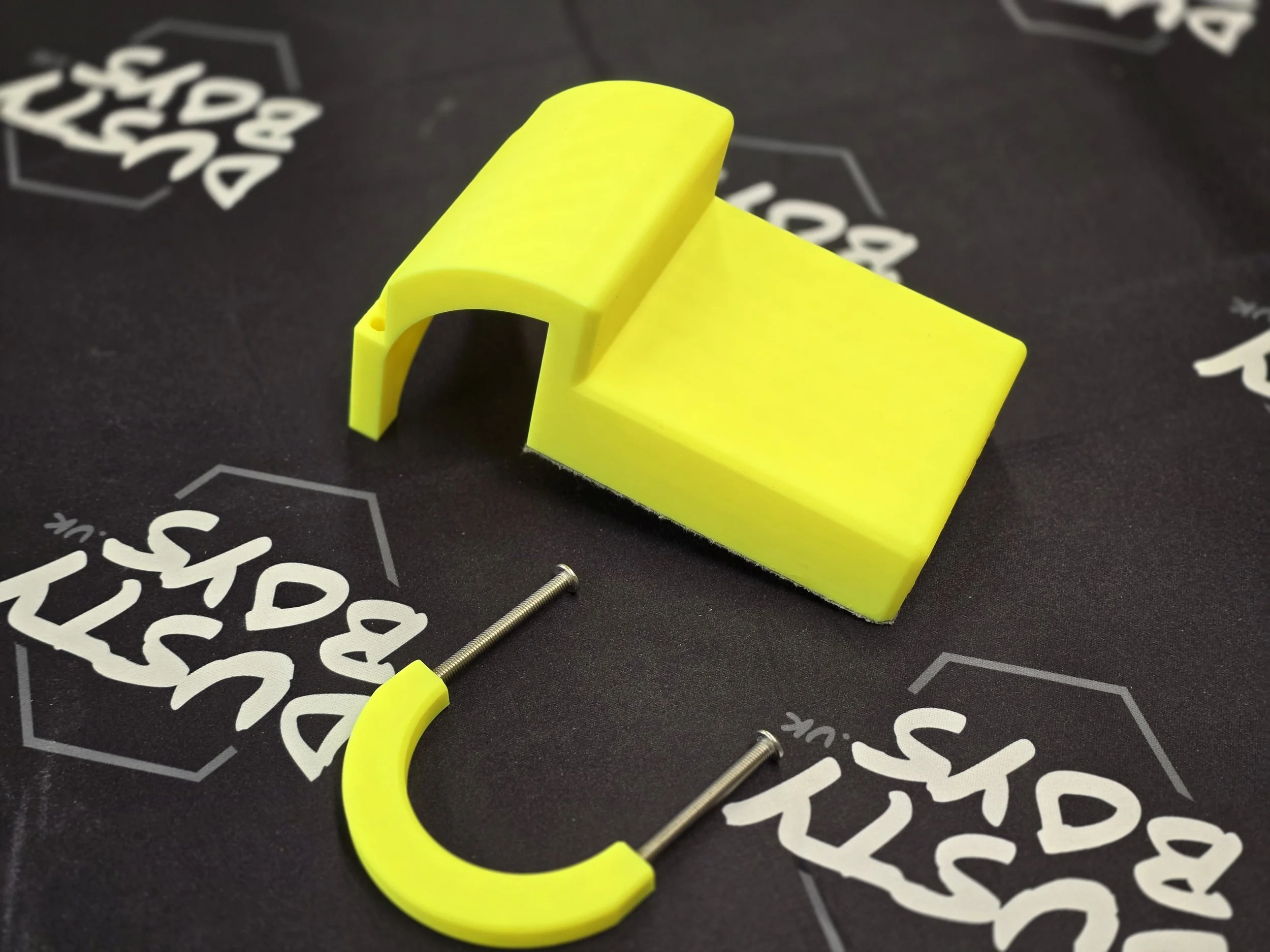 The edge guide disassembled, showing the felt-padded body, curved mounting bracket, and two screws