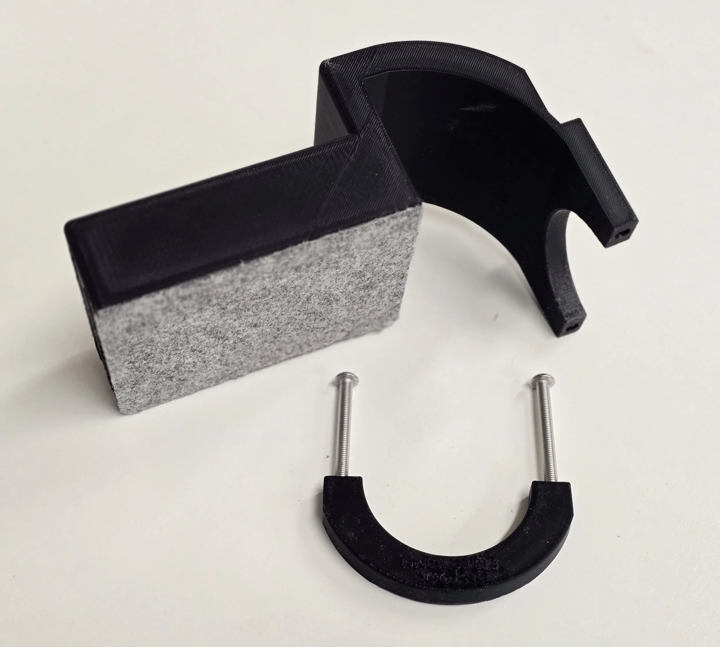 The edge guide disassembled, showing the felt contact pad, curved bracket, and mounting screws