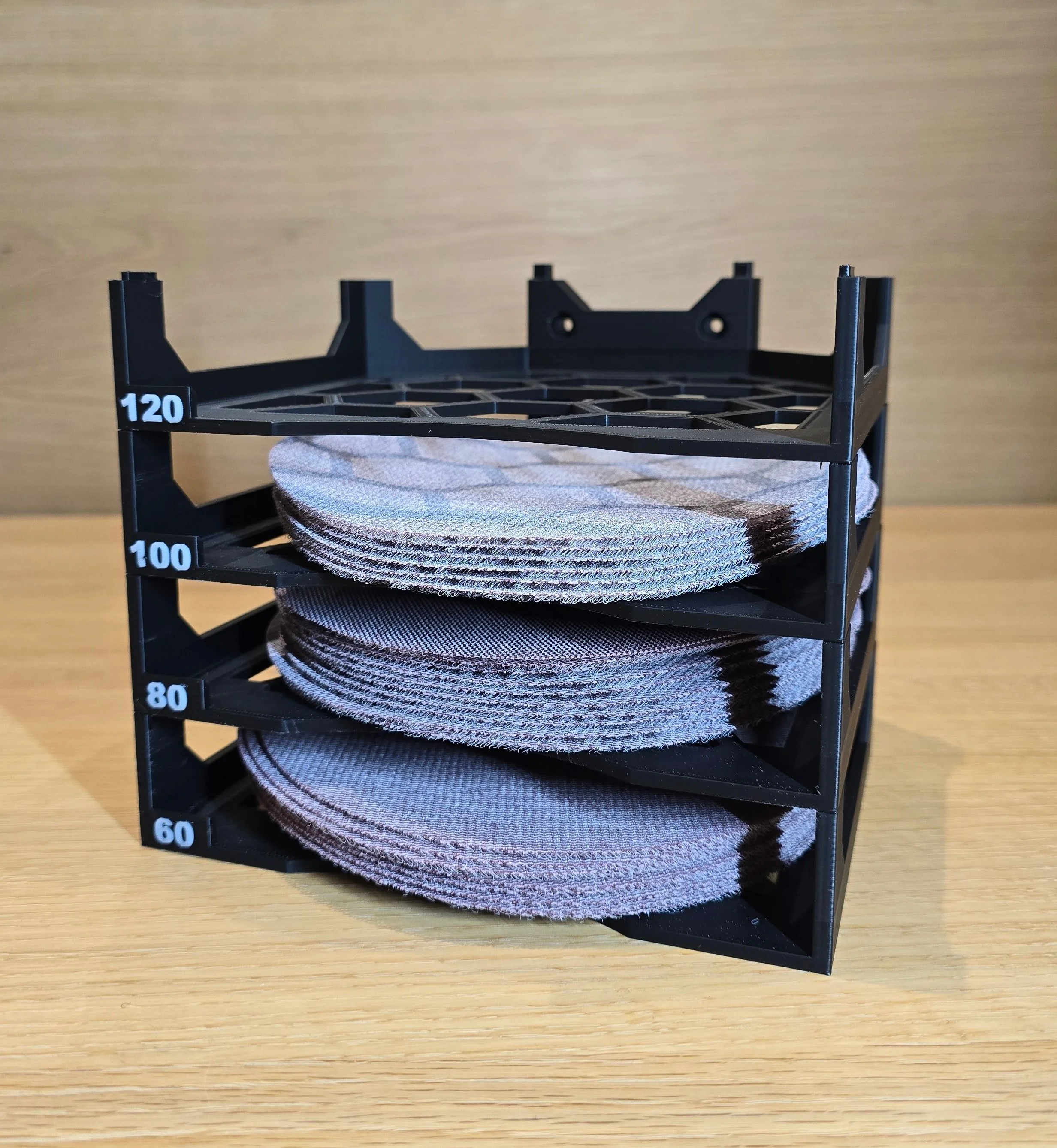 Four tiers of the Motam sanding disc holder stacked and loaded with 120, 100, 80, and 60 grit orbital sanding discs