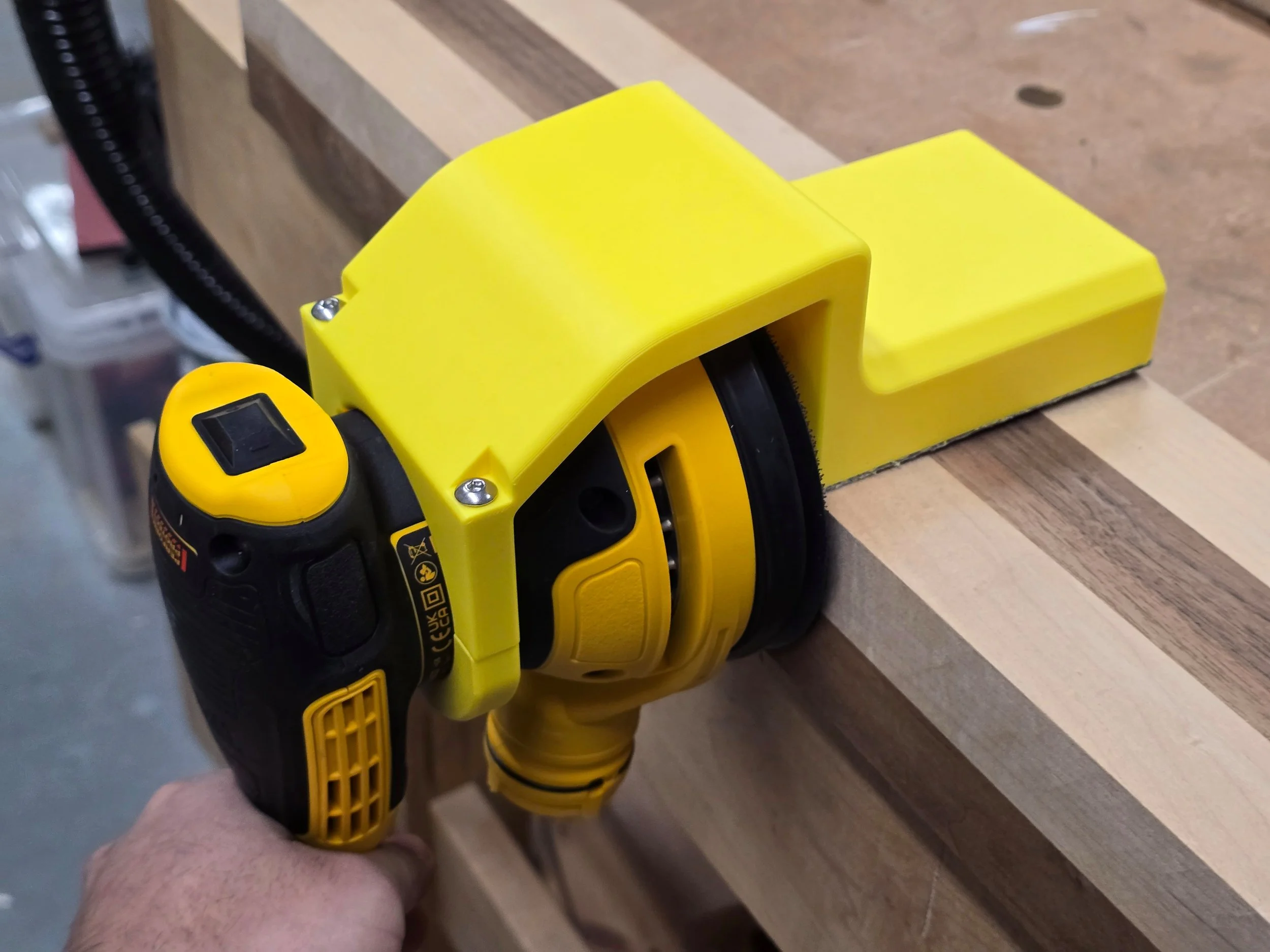 The Motam 90-degree edge guide fitted to a Dewalt DWE6423 sander, sanding the edge of a wooden board